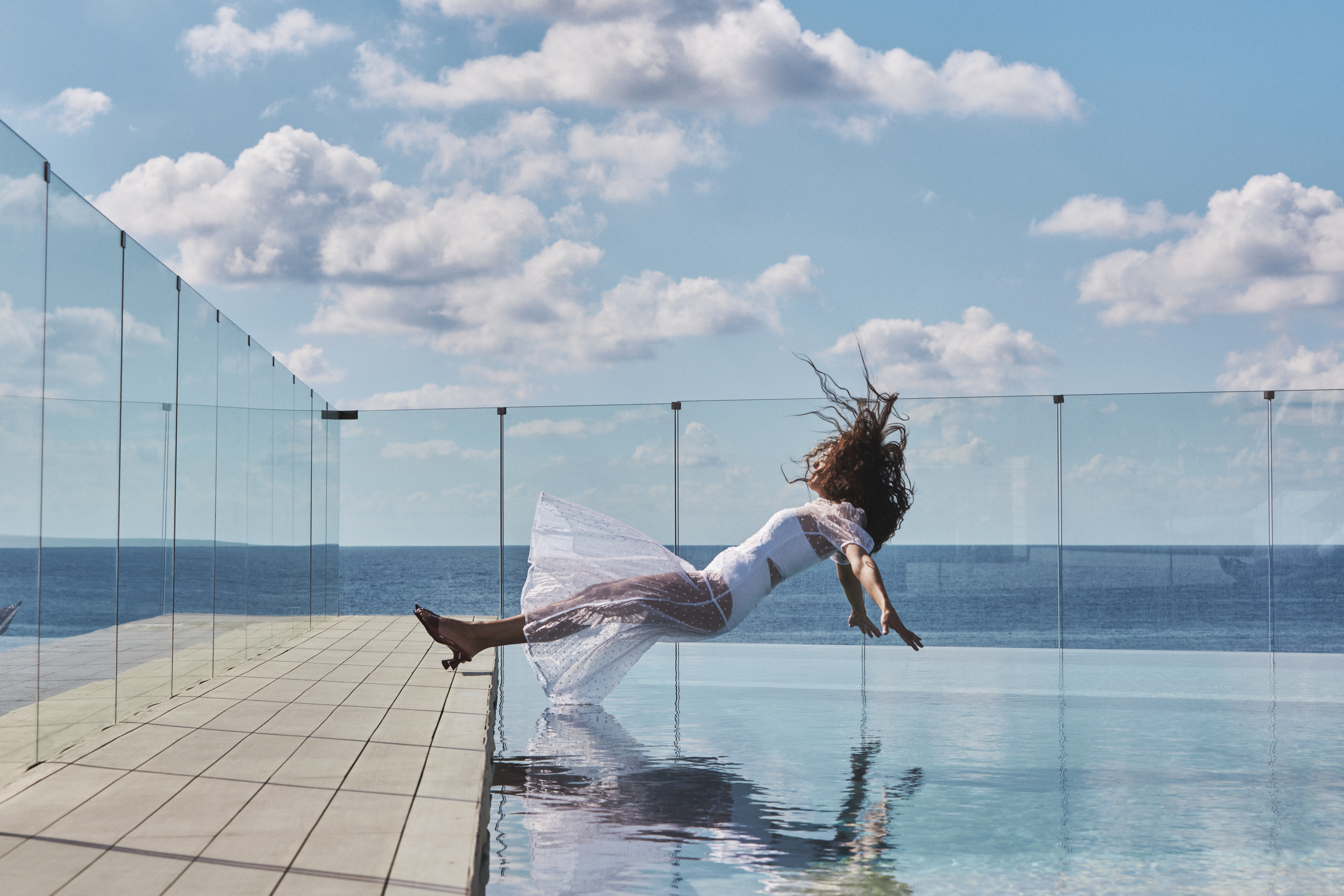 a woman in a white dress jumping into a pool of water