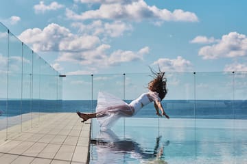 a woman in a white dress jumping into a pool of water