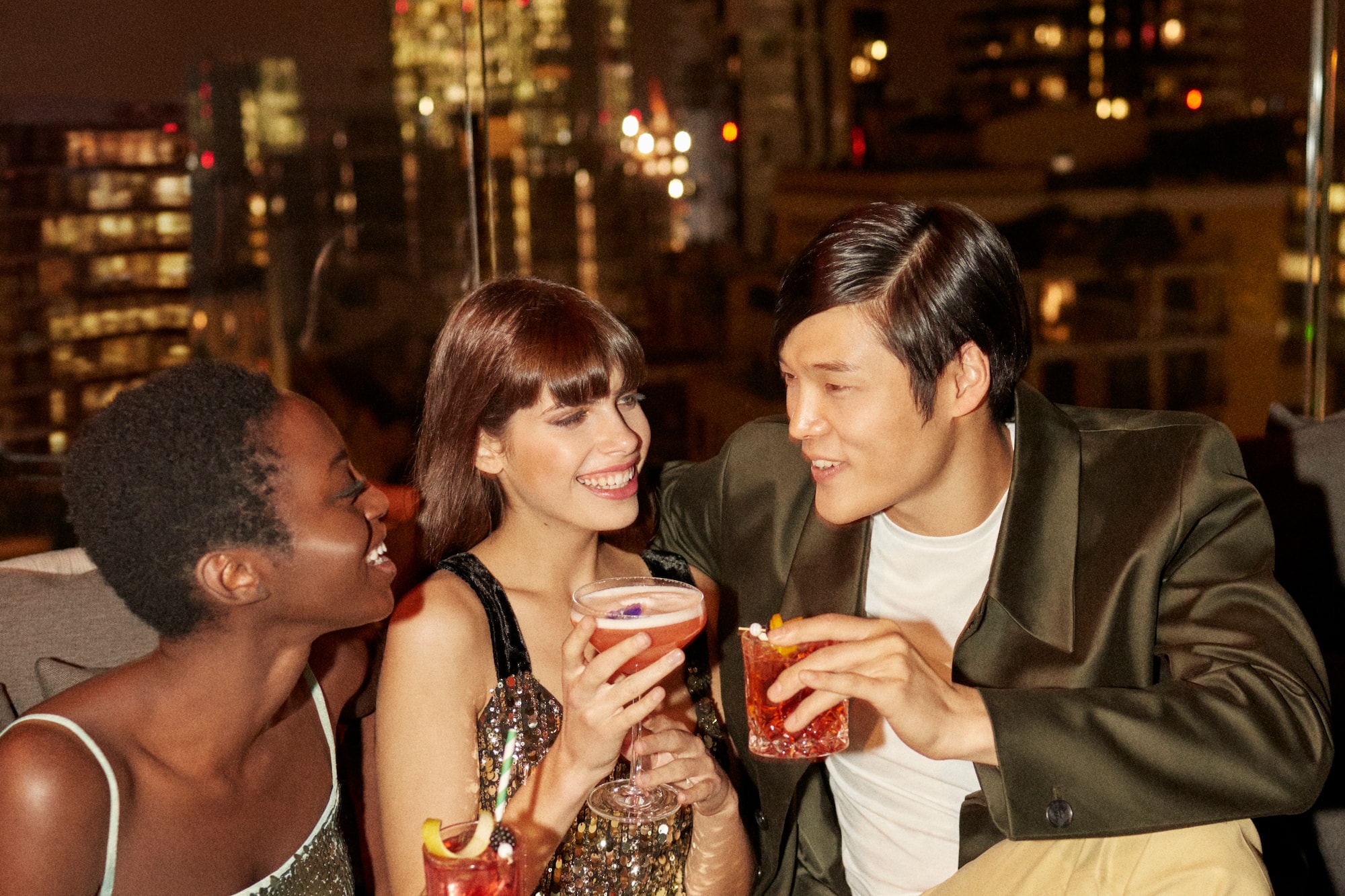 A group of people gathered around a table, each with a drink in hand.