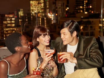 A group of people gathered around a table, each with a drink in hand.