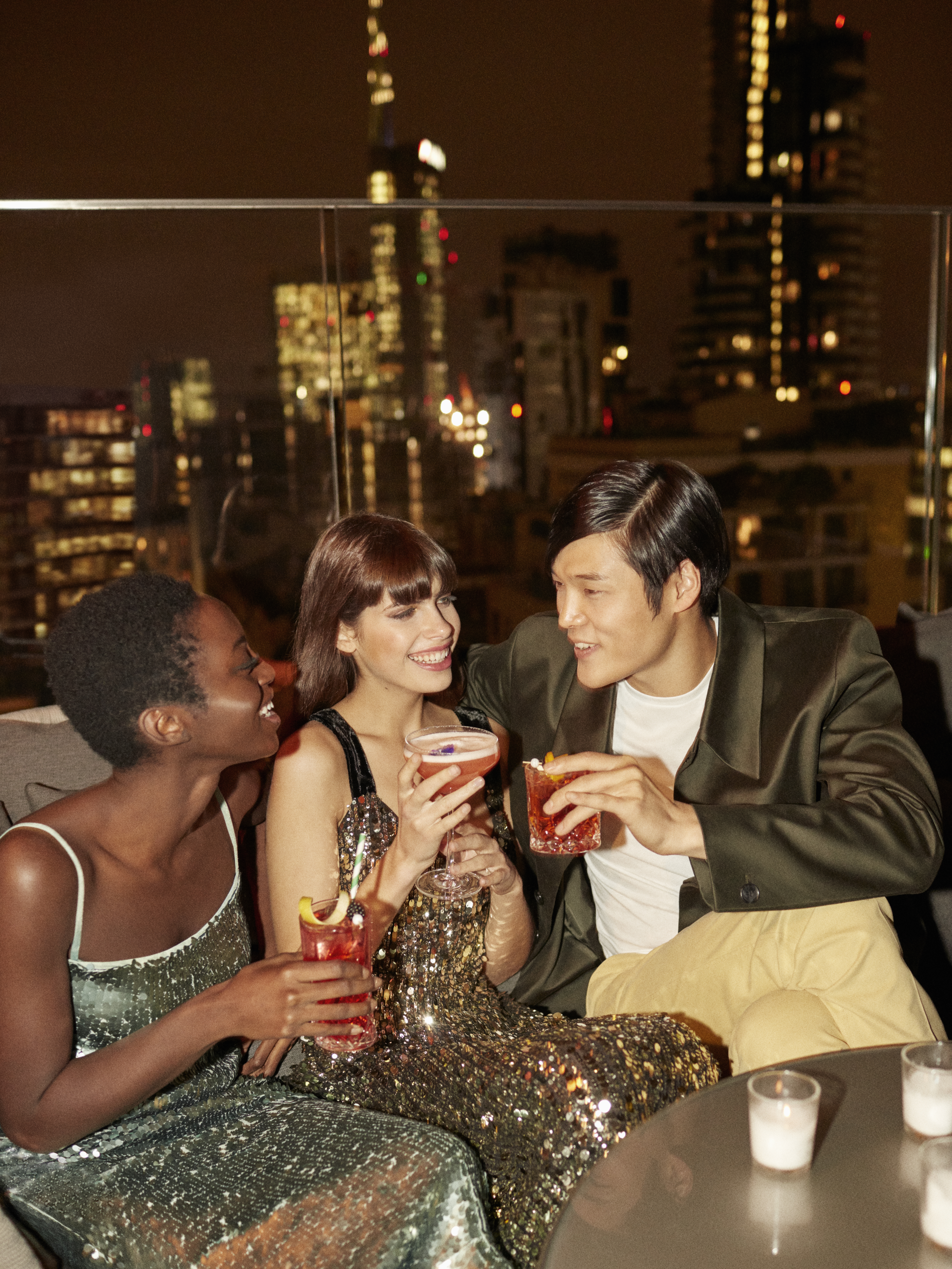A group of people gathered around a table, each with a drink in hand.