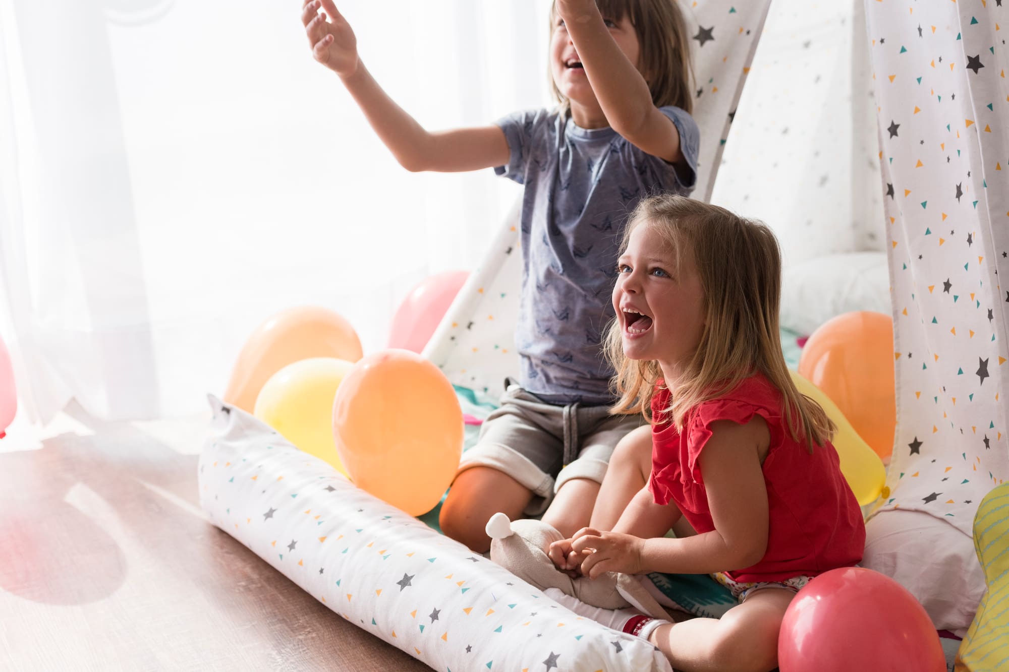 a couple of children sitting on a floor with balloons