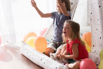 a couple of children sitting on a floor with balloons