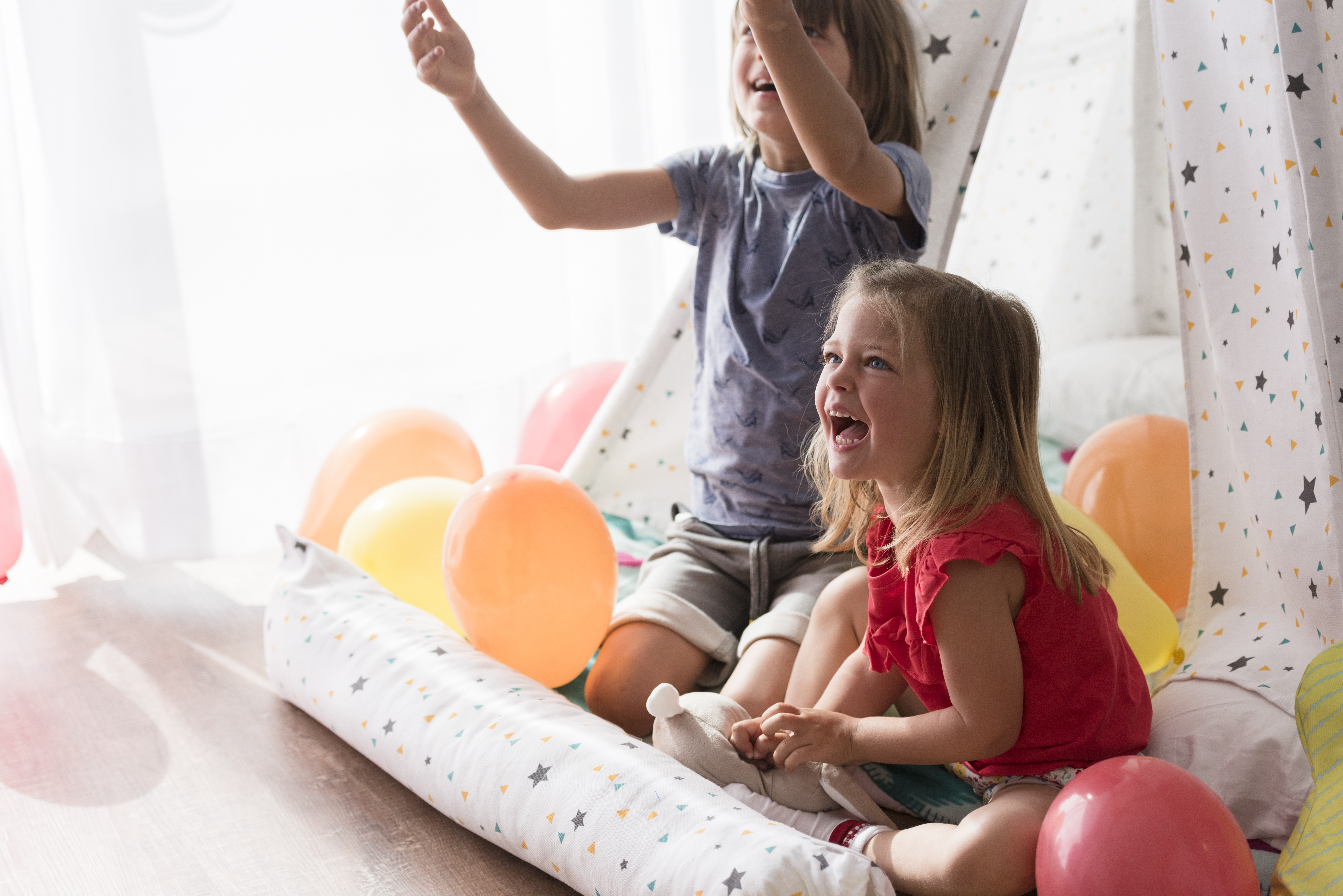 a couple of children sitting on a floor with balloons
