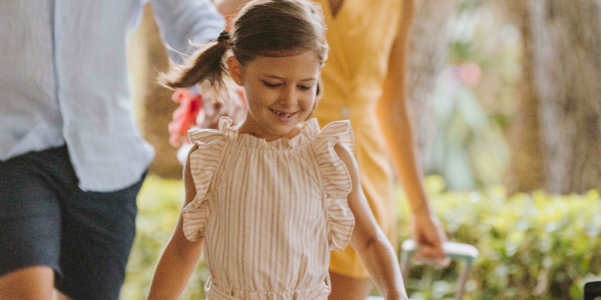 A girl runs with a man and a woman in the background.
