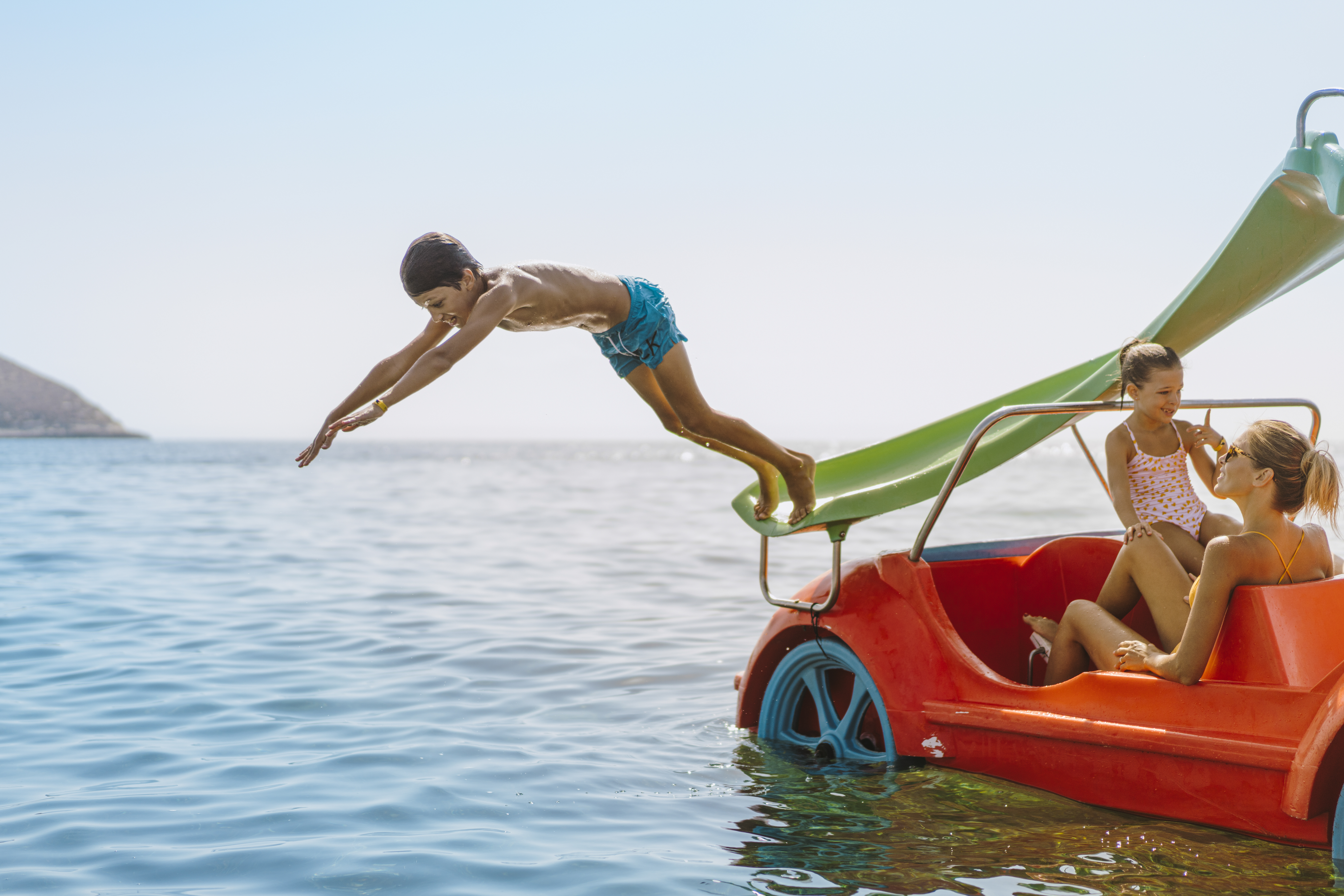 a boy jumping off a slide into a boat
