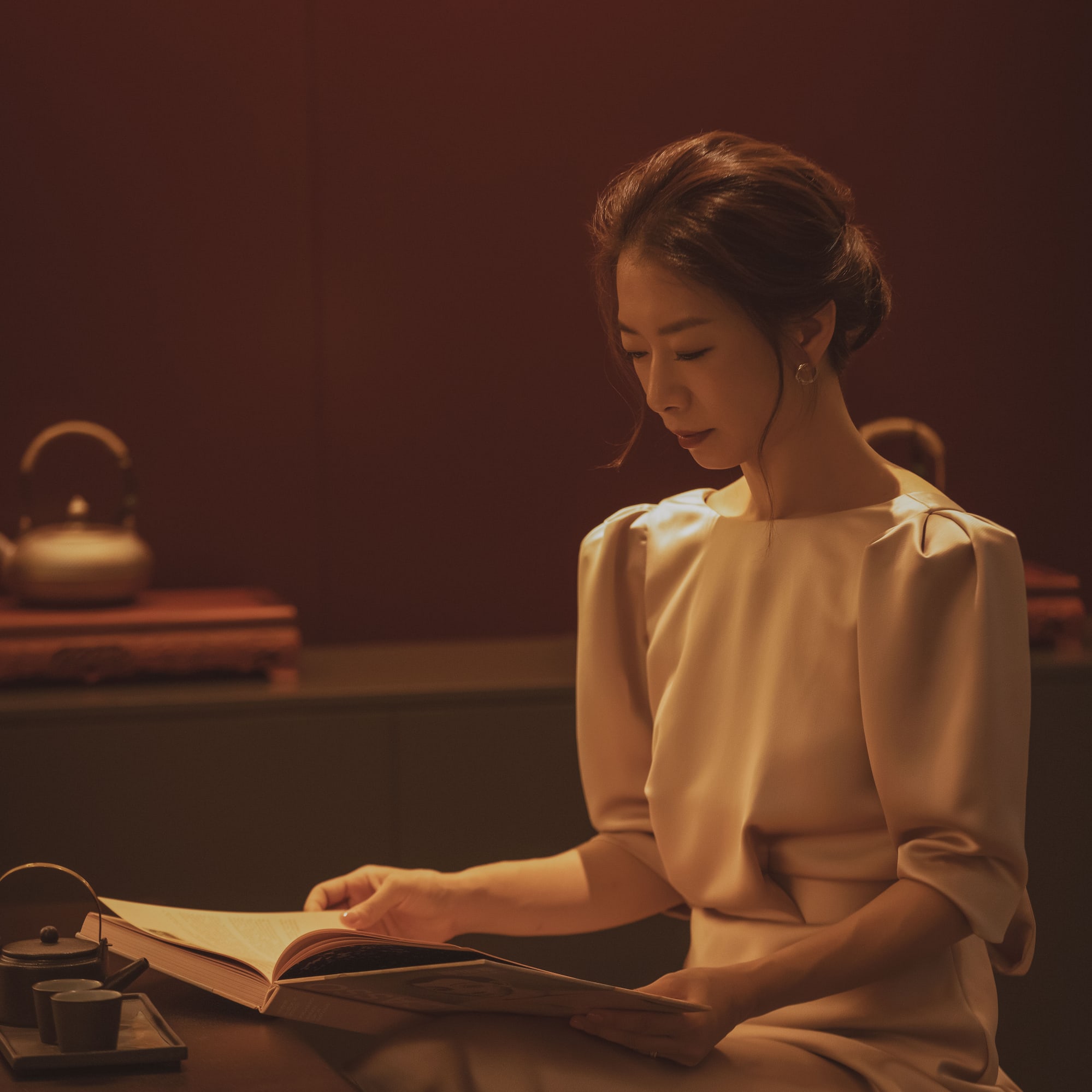 a woman sitting at a table reading a book