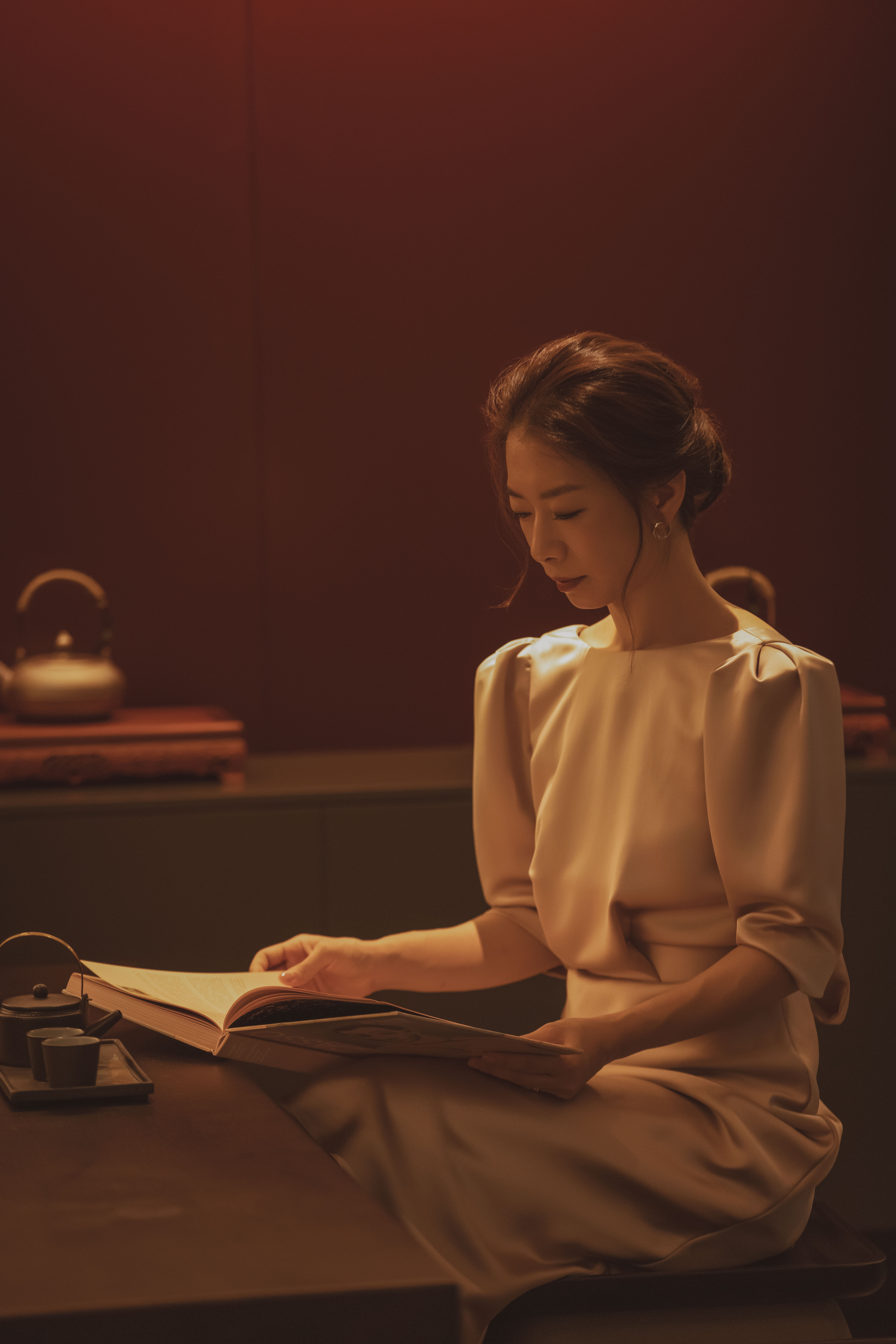 a woman sitting at a table reading a book