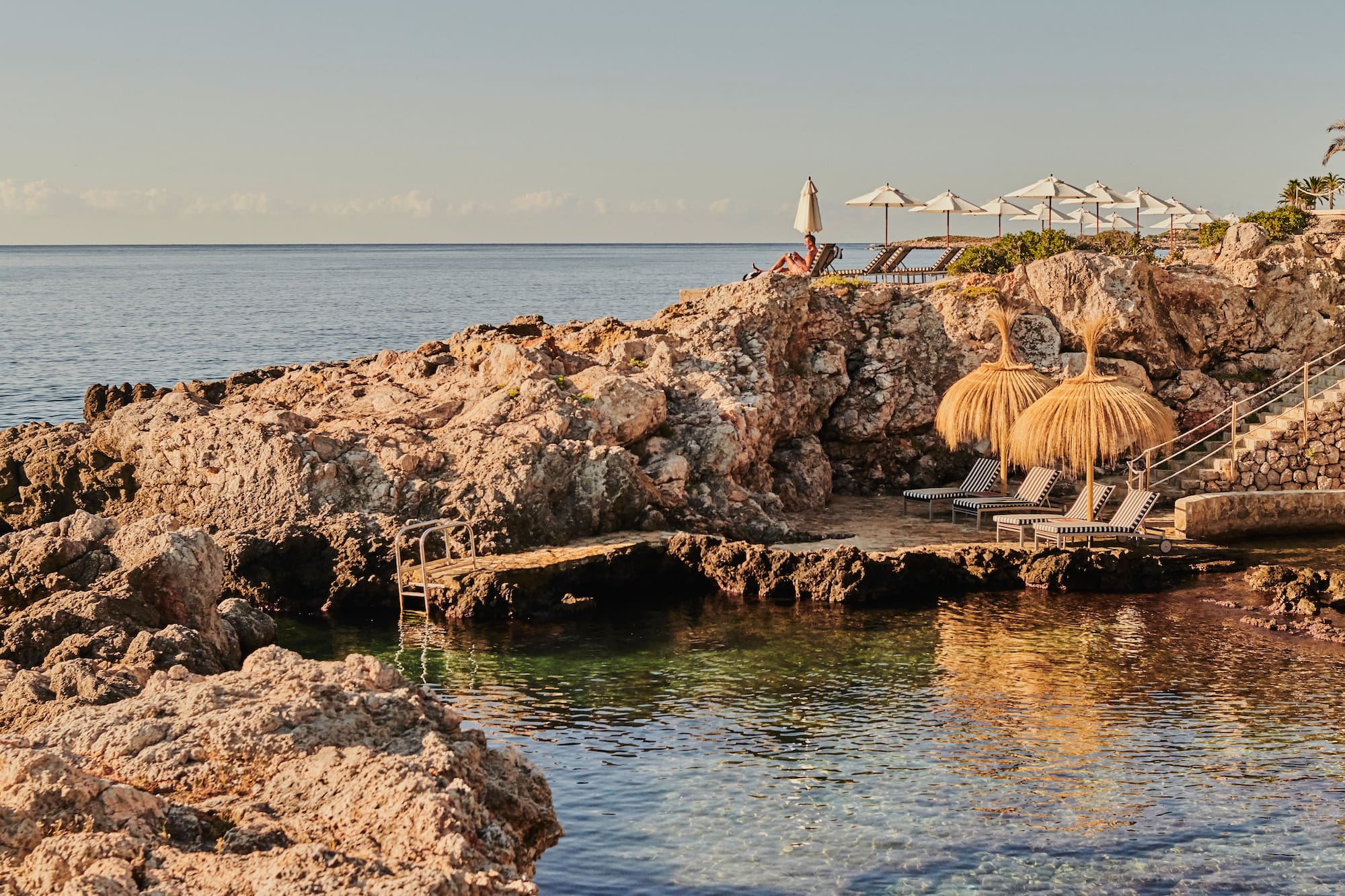 a beach with a couple of umbrellas and chairs on a rocky beach