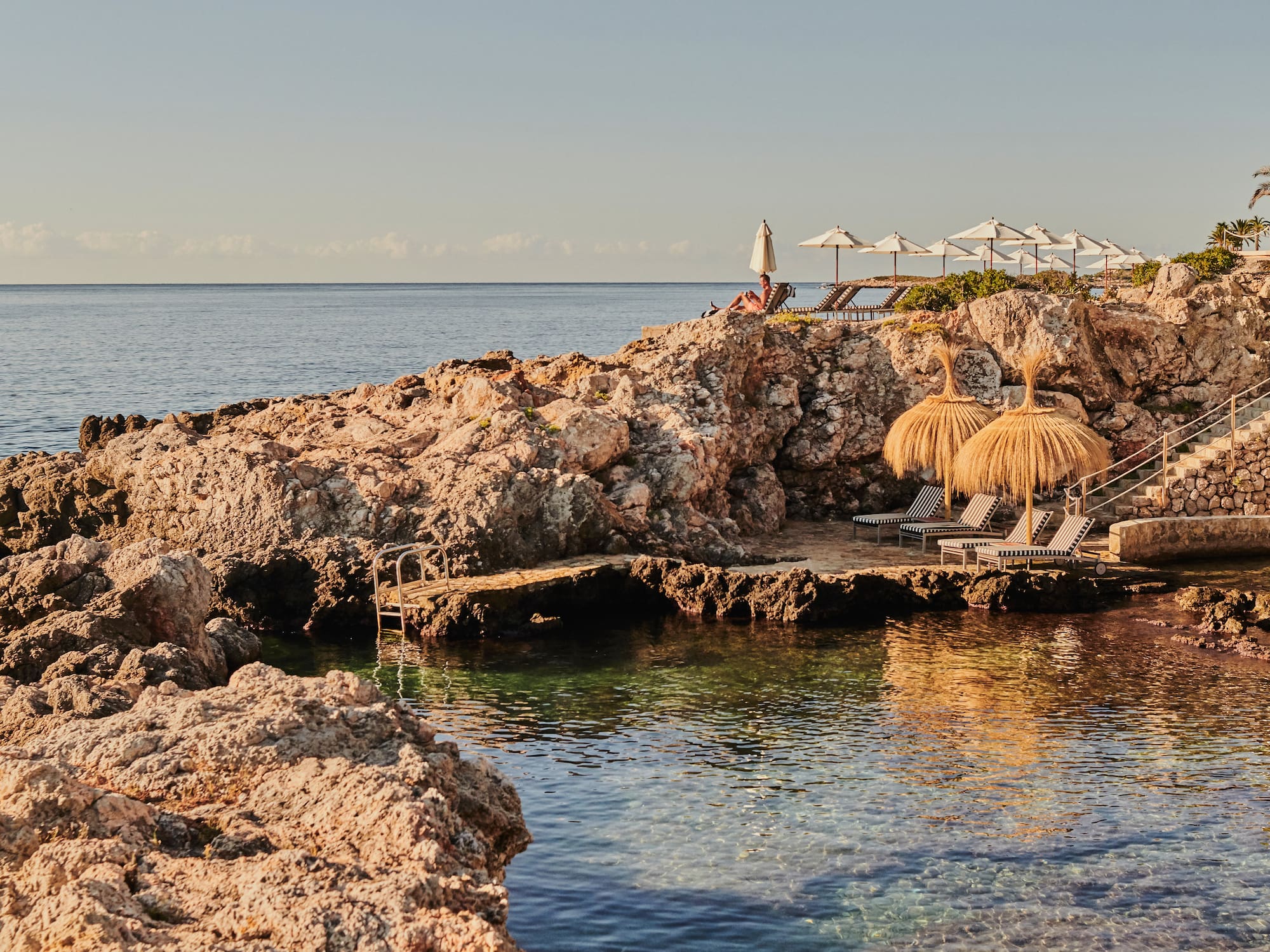 a beach with a couple of umbrellas and chairs on a rocky beach