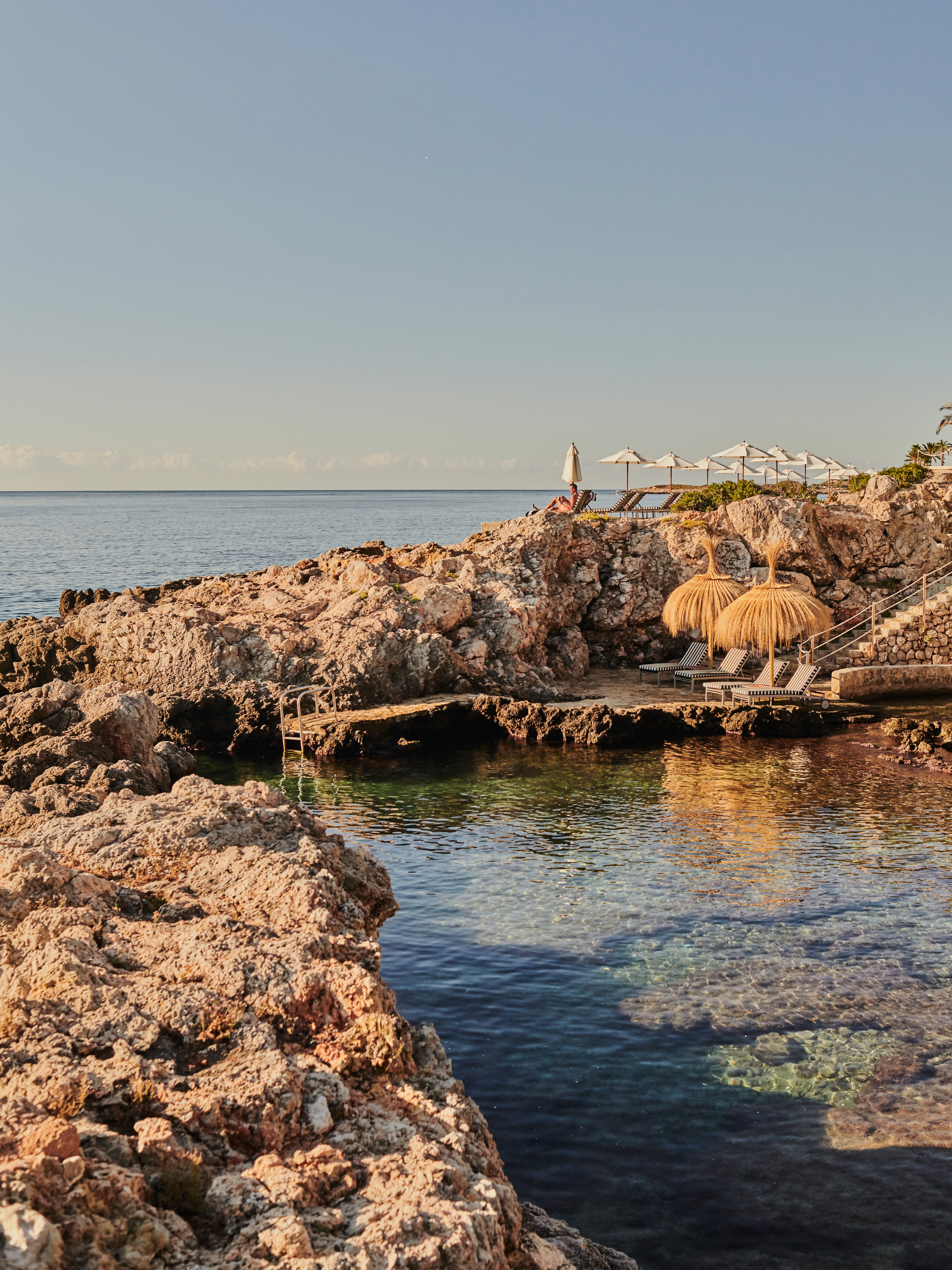 a beach with a couple of umbrellas and chairs on a rocky beach