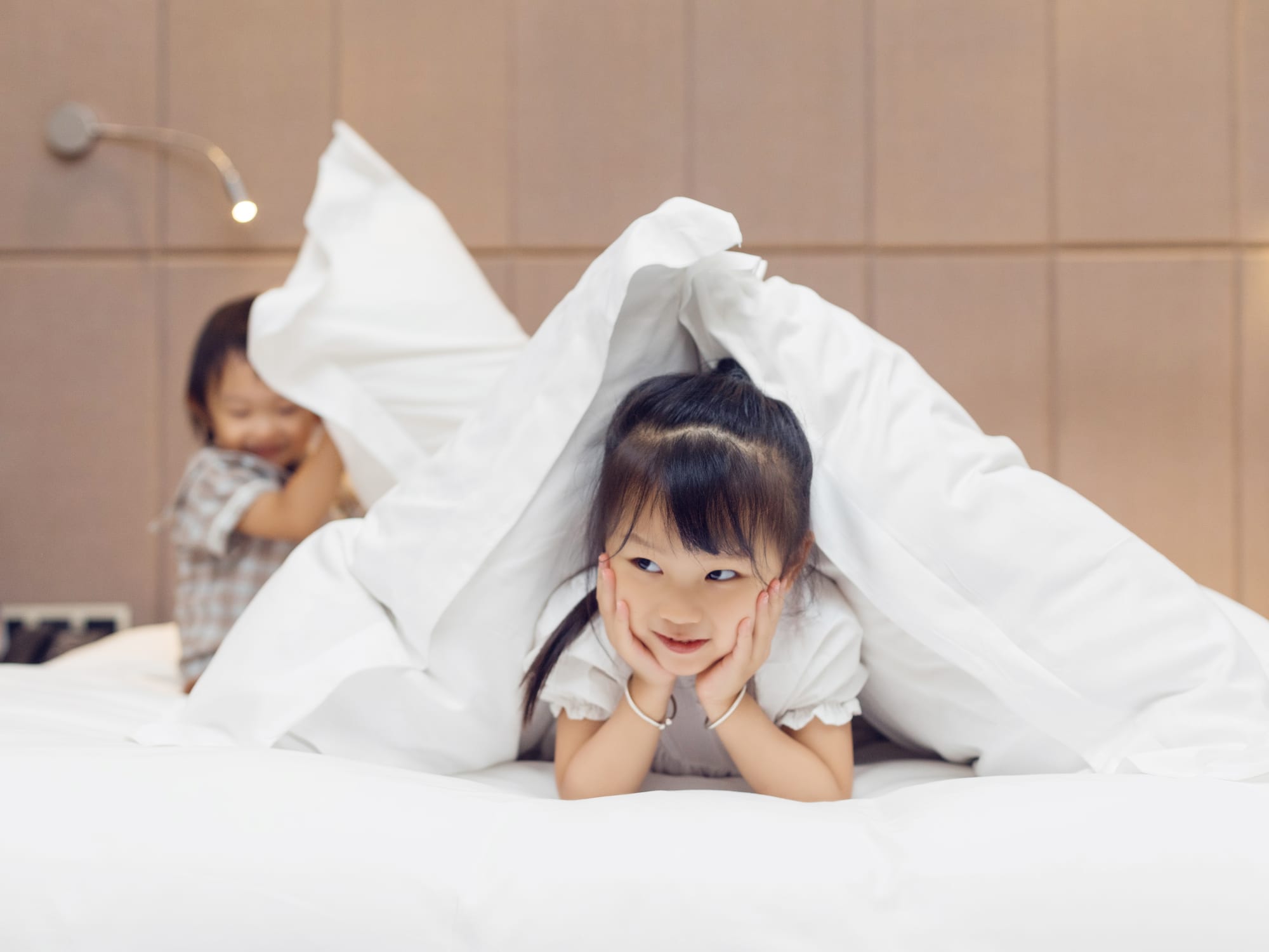 a girl lying on a bed under a blanket
