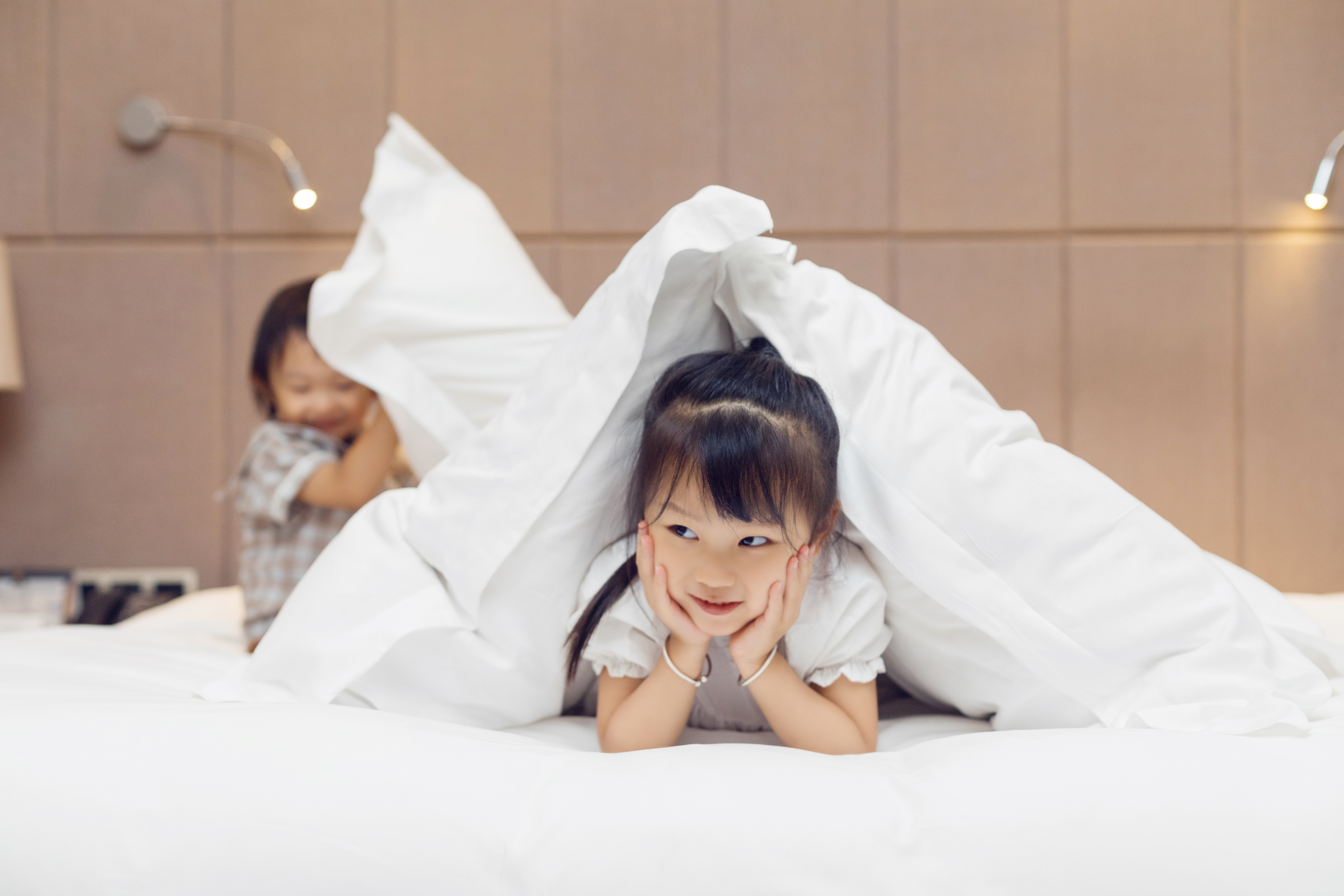 a girl lying on a bed under a blanket