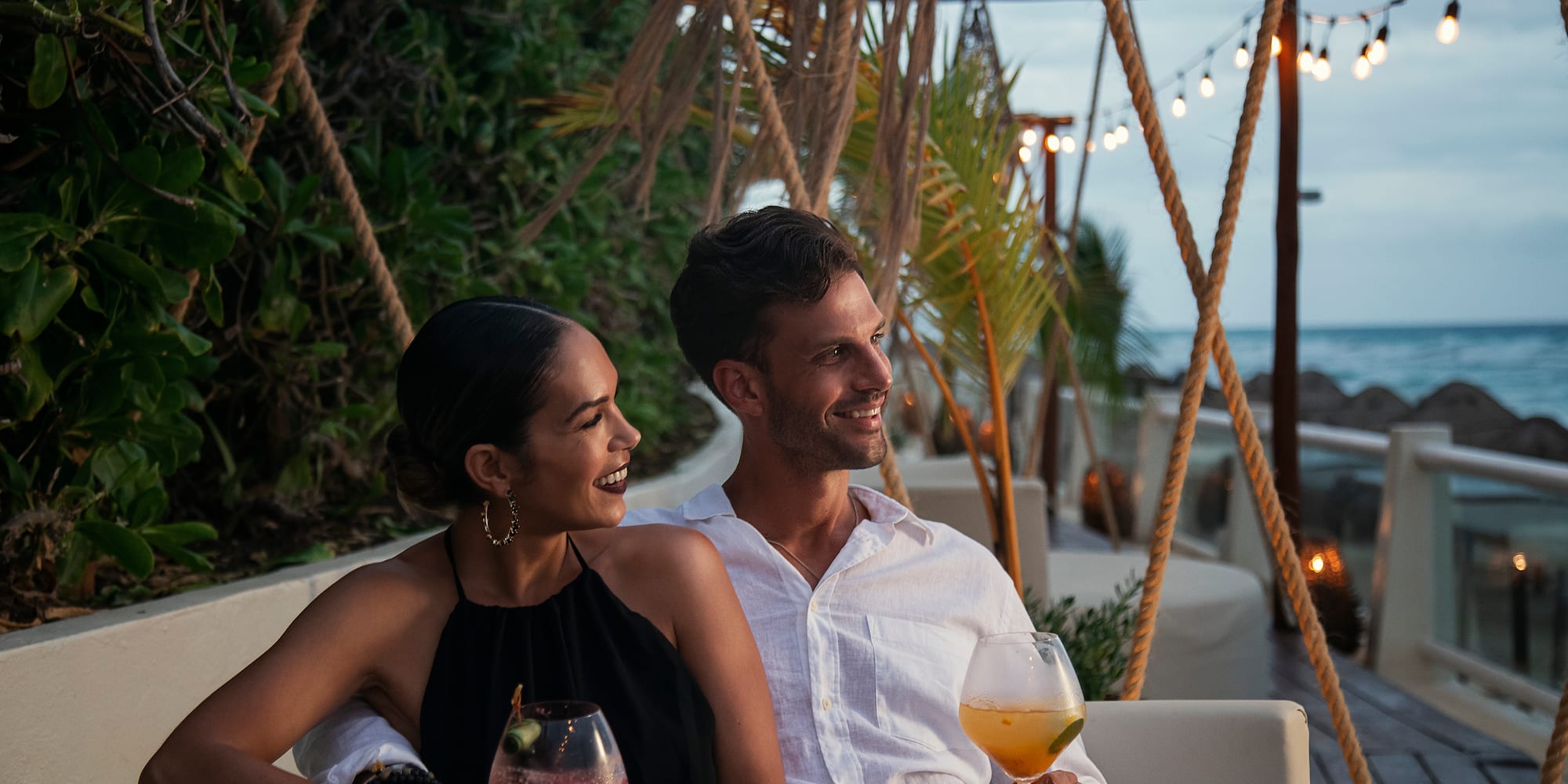 a man and woman sitting on a couch with drinks