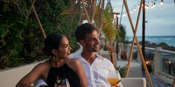 a man and woman sitting on a couch with drinks