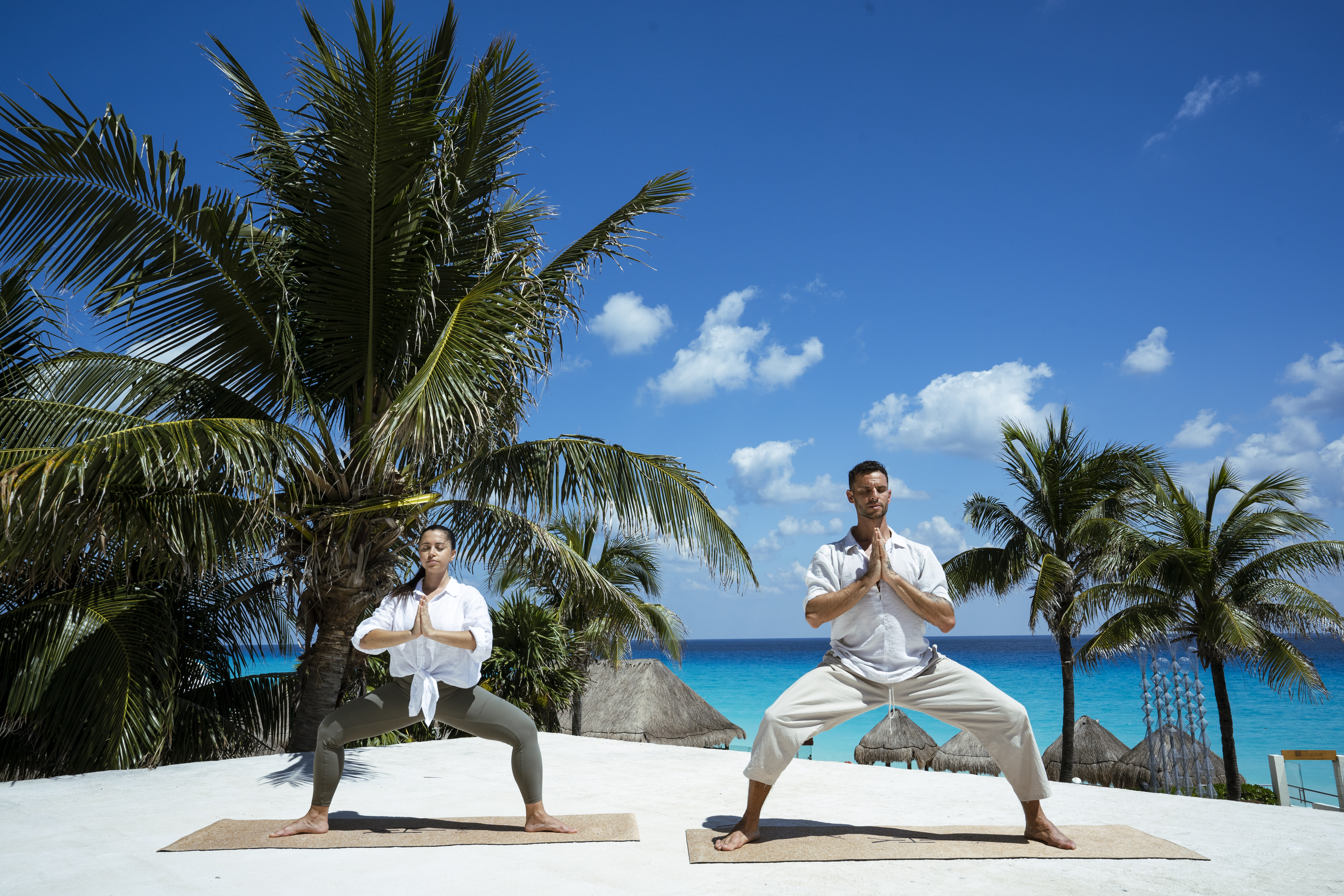 a man and woman doing yoga on a beach