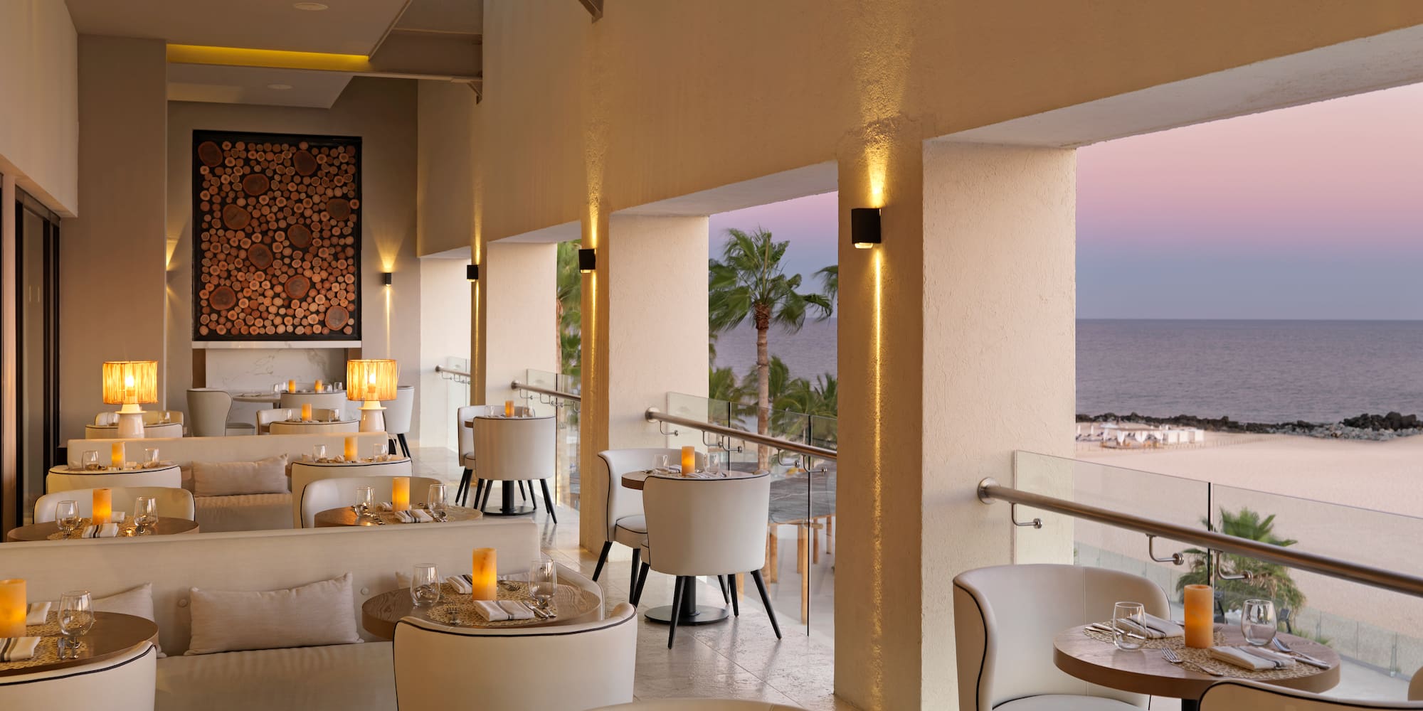 a room with tables and chairs and a view of the ocean