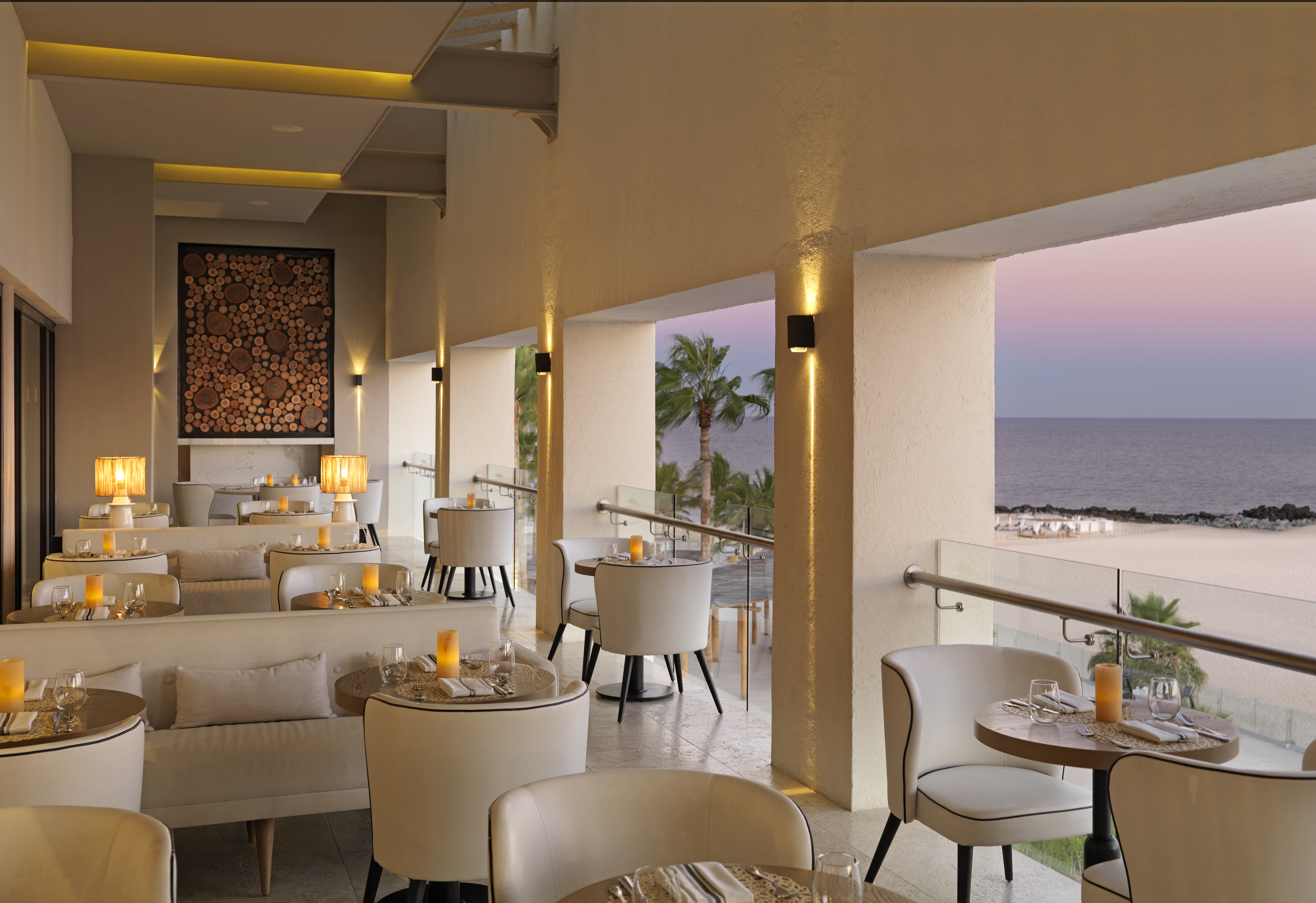 a room with tables and chairs and a view of the ocean