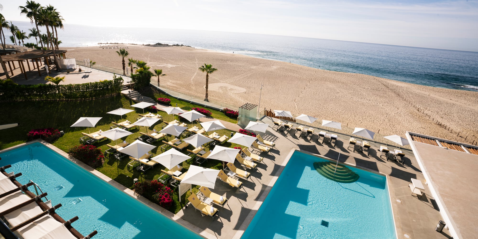 a pool with umbrellas and chairs on the beach