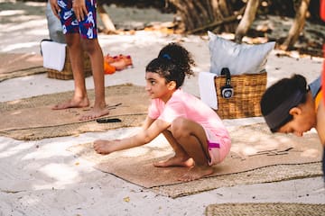 a girl kneeling on mat on the sand