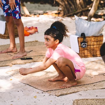 a girl kneeling on mat on the sand