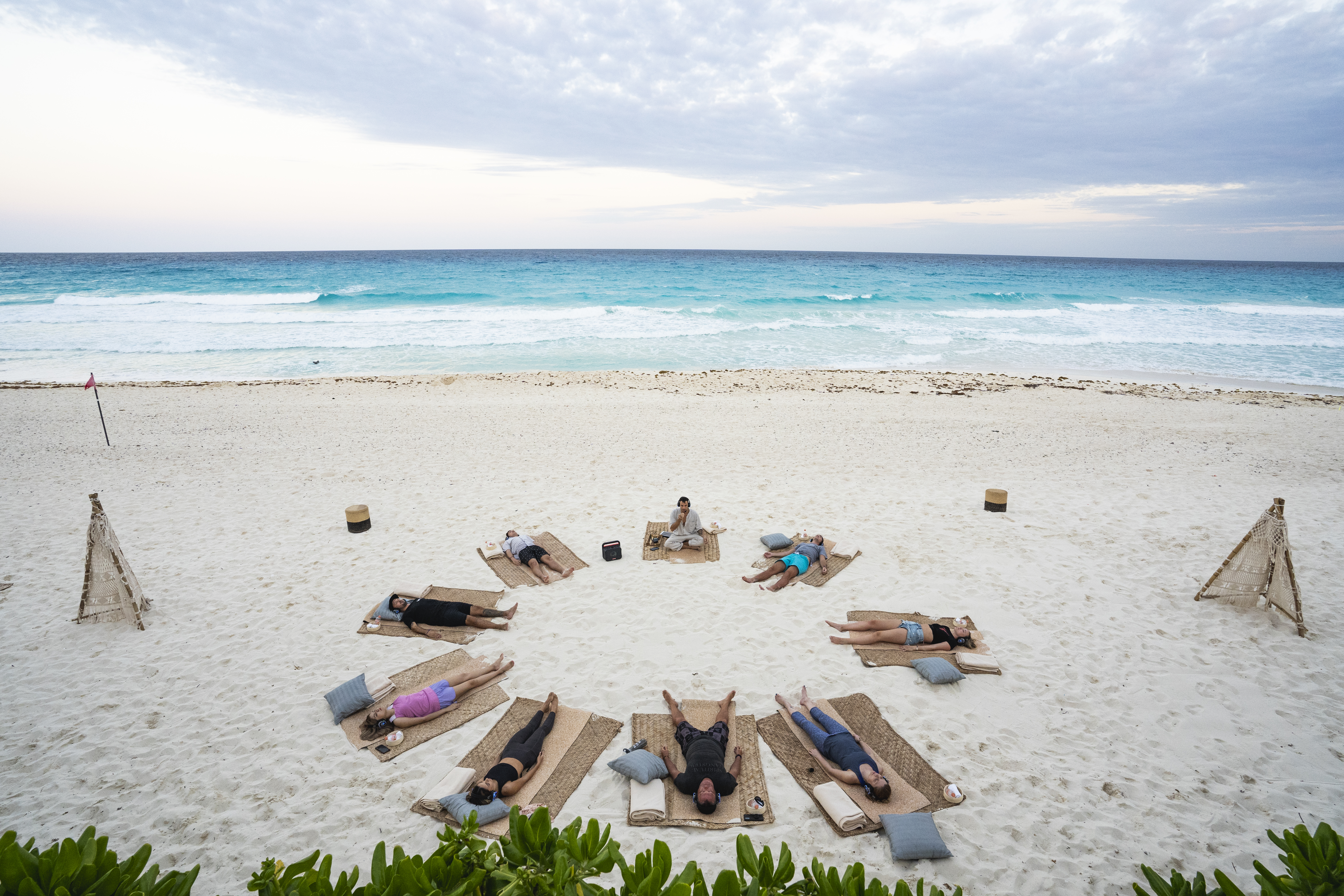 a group of people lying on mats on a beach
