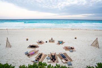 a group of people lying on mats on a beach