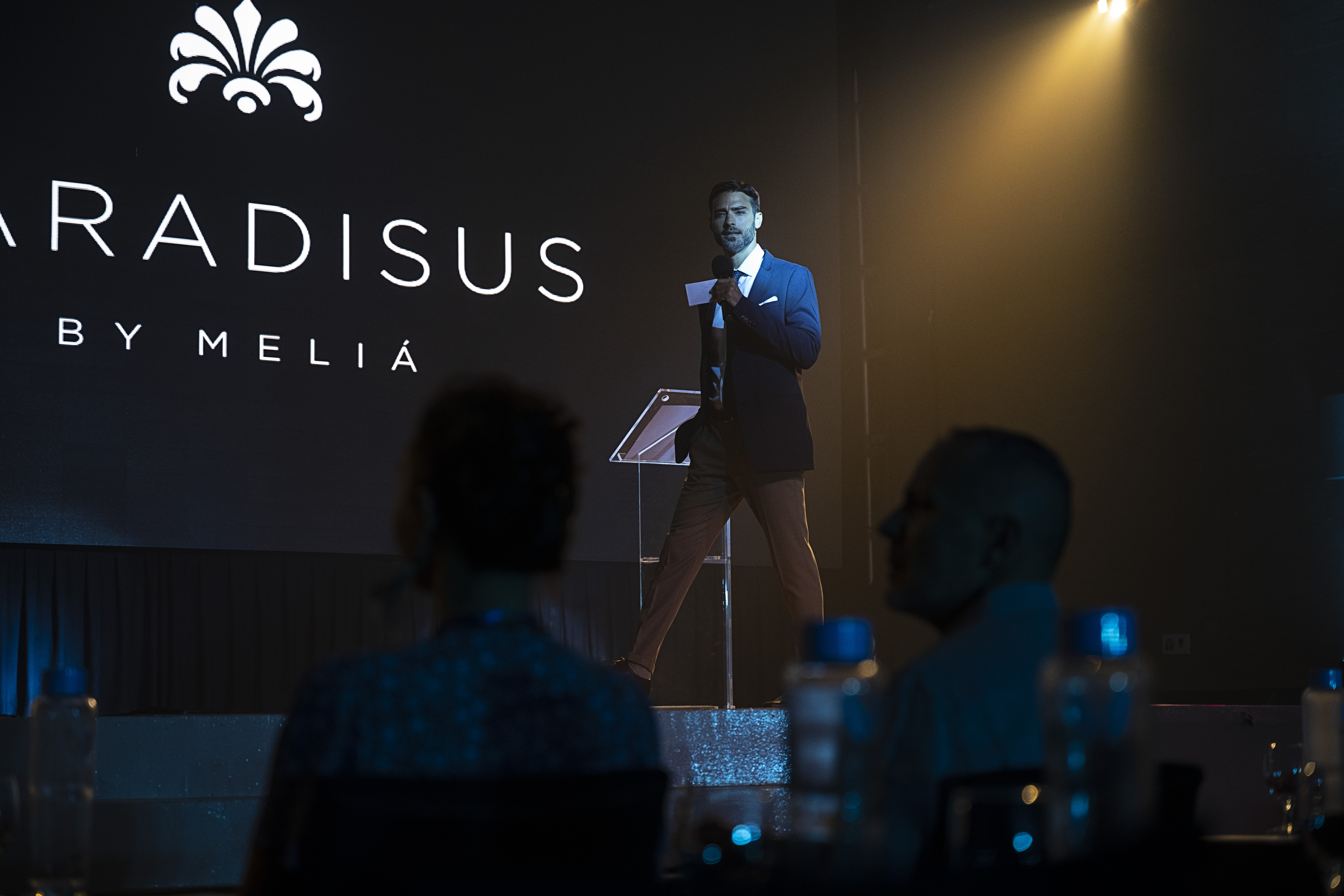 Man speaking on stage at a conference, Paradissus by Meliá logo visible.