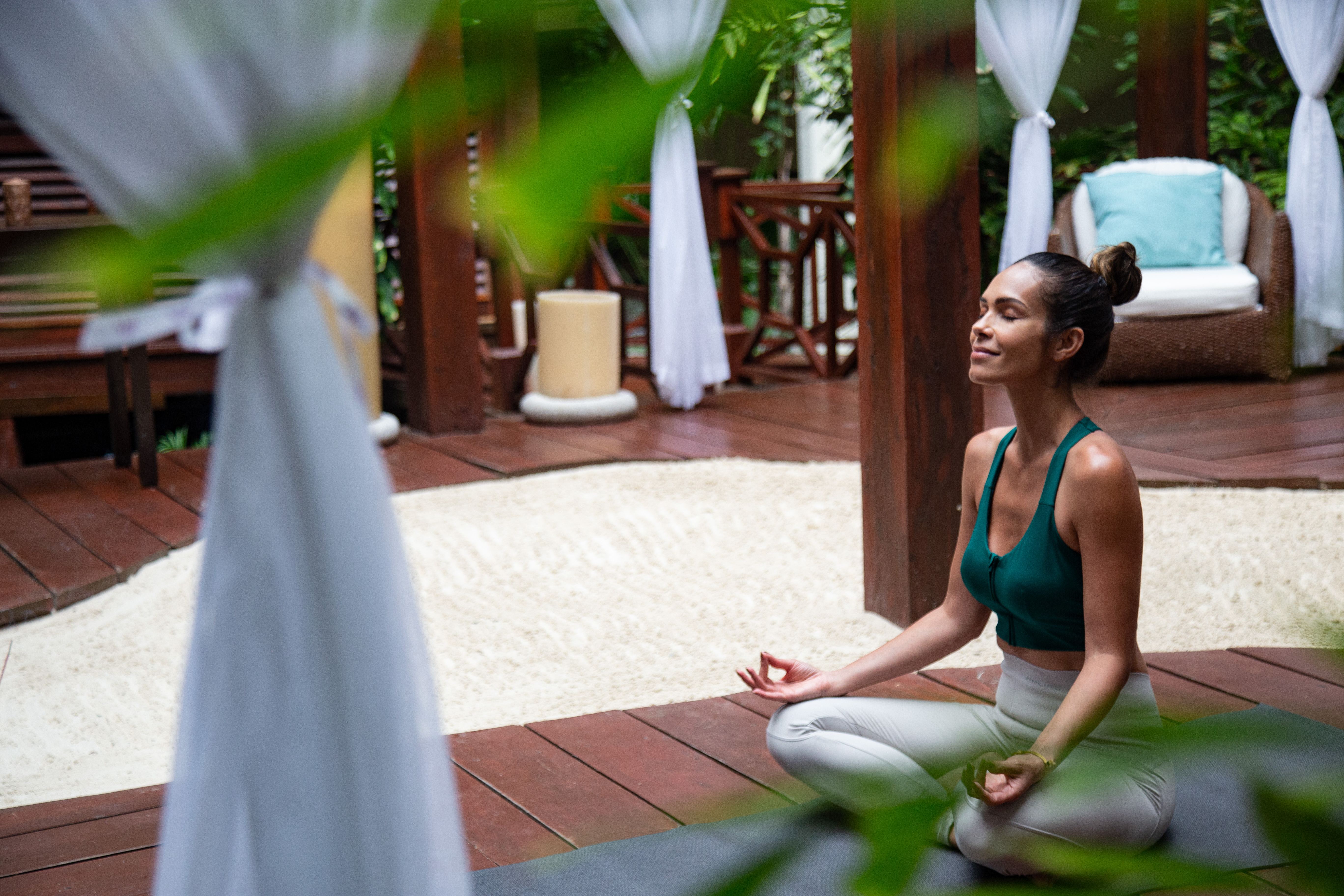 Serene woman meditating on yoga mat in outdoor wellness gazebo.
