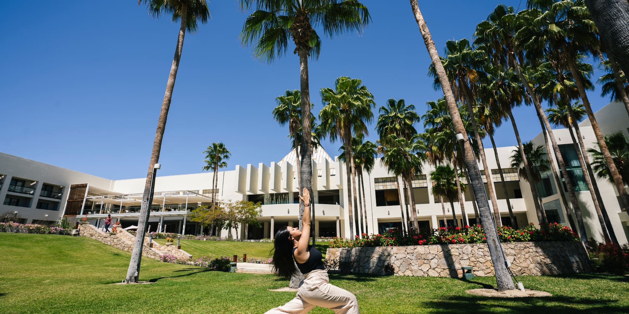a woman doing yoga outside with palm trees