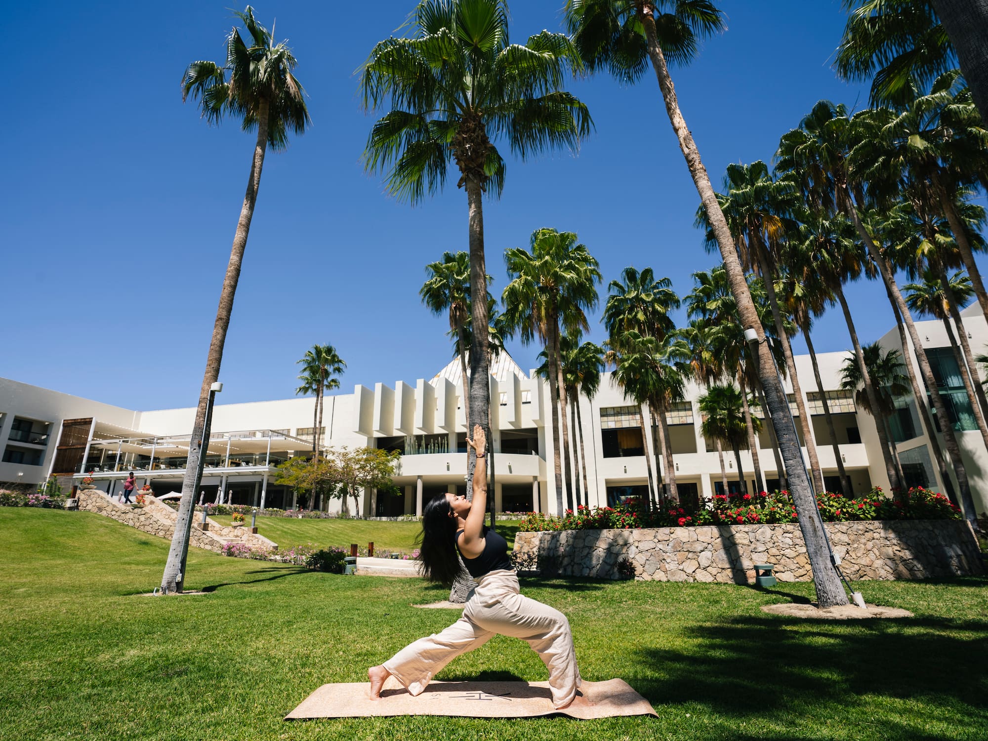 a woman doing yoga outside with palm trees
