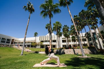 a woman doing yoga outside with palm trees