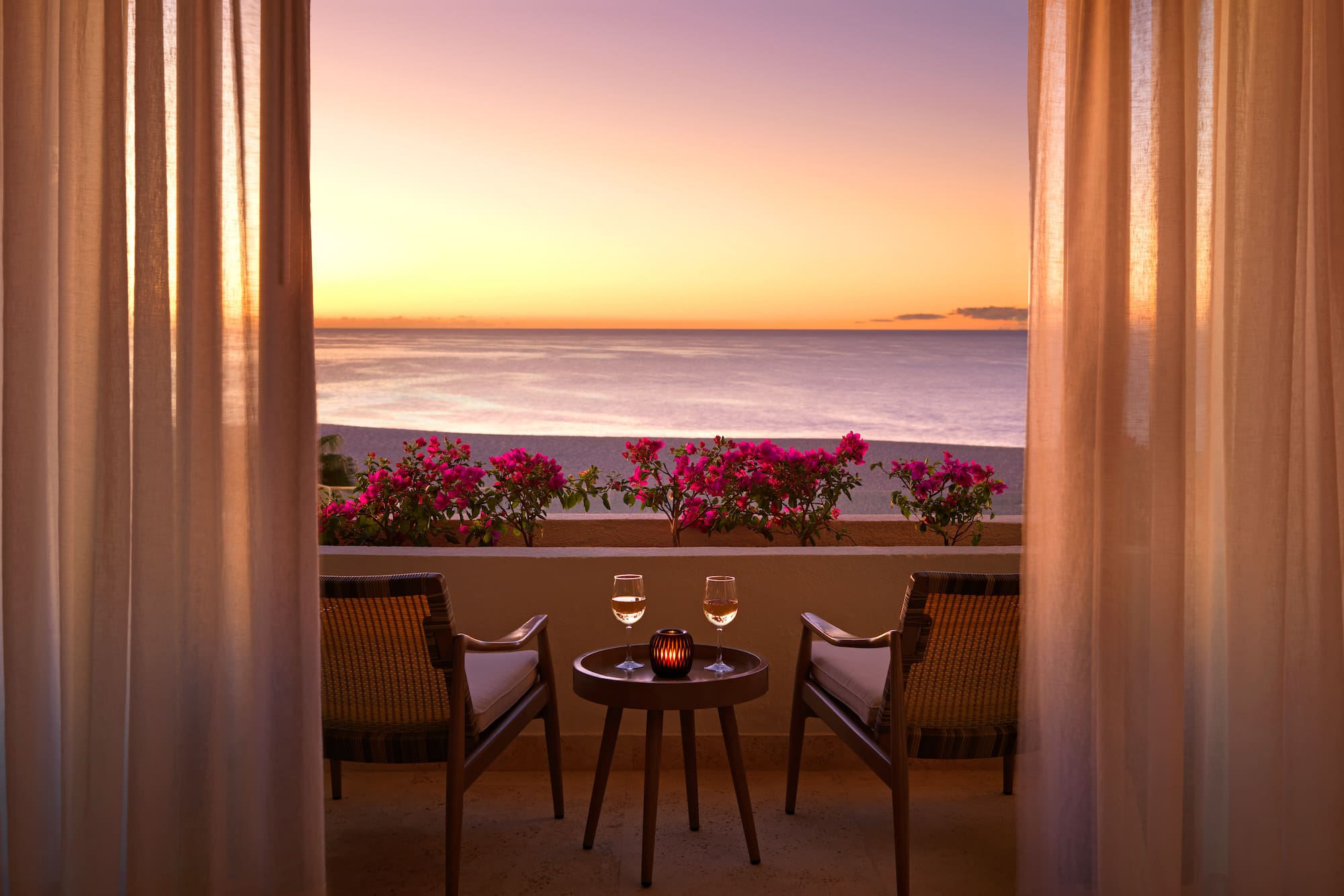 a table and chairs on a balcony overlooking the ocean