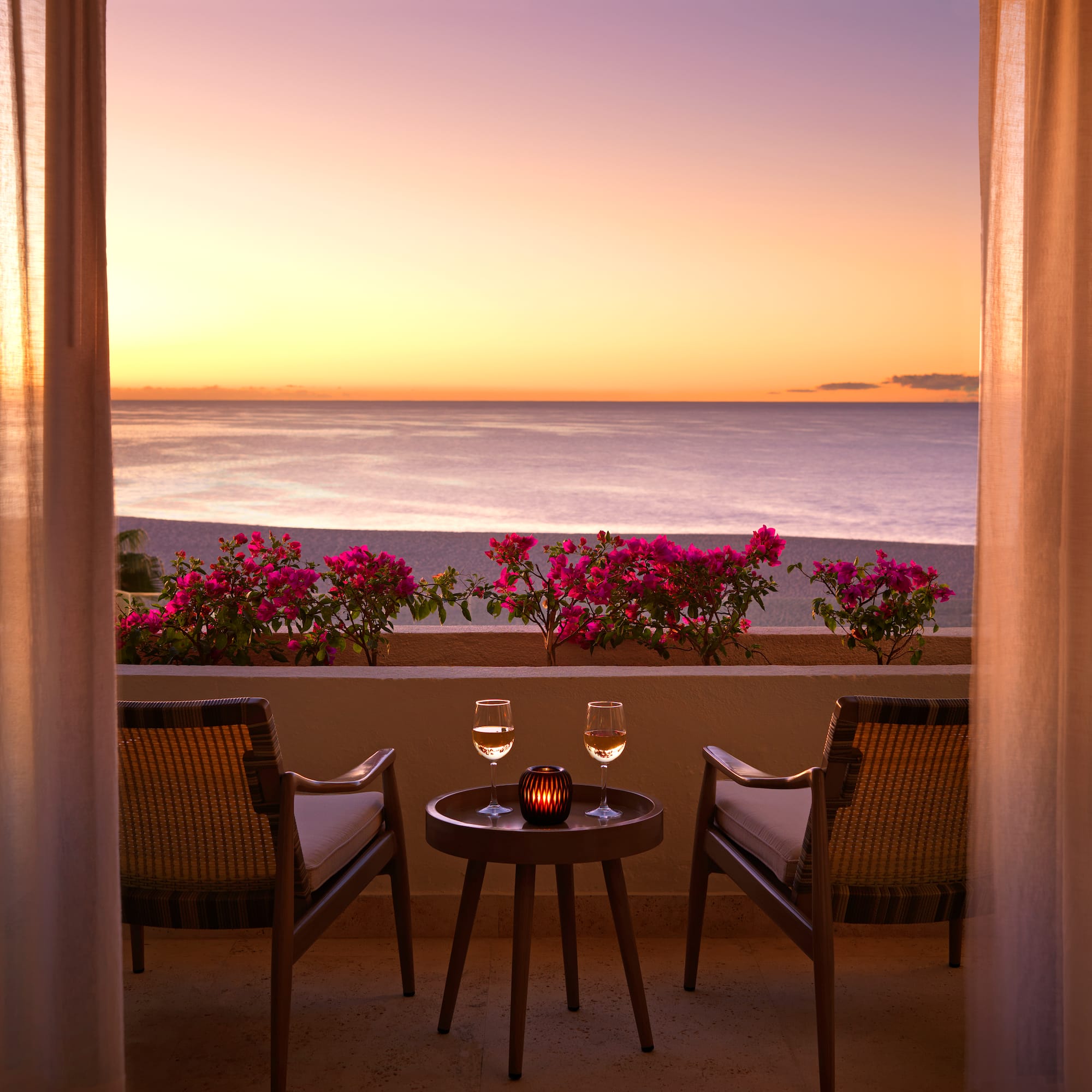 a table and chairs on a balcony overlooking the ocean