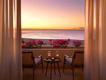 a table and chairs on a balcony overlooking the ocean