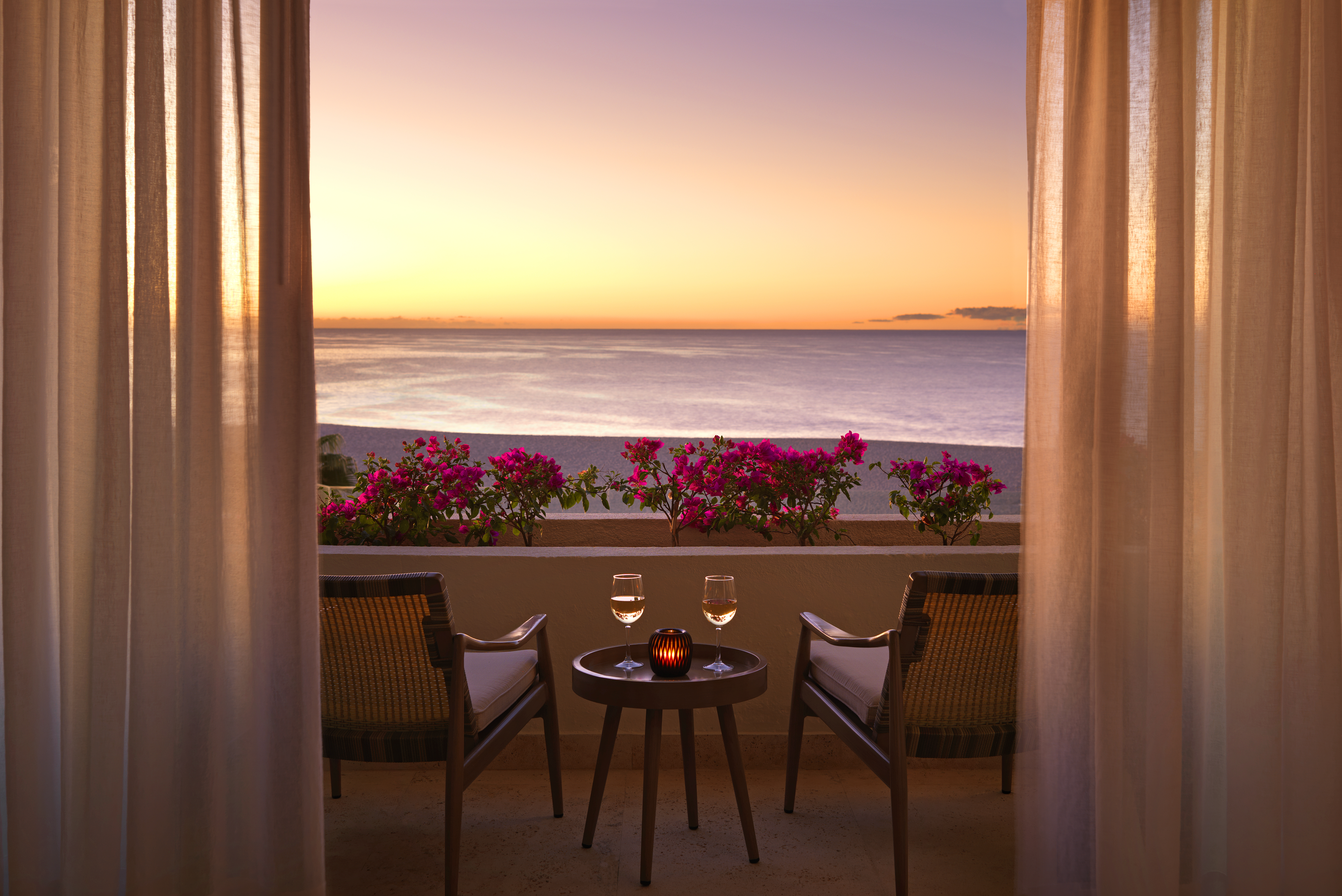 a table and chairs on a balcony overlooking the ocean