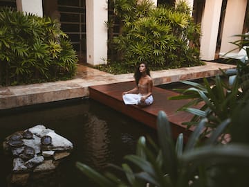 a woman sitting on a wood platform in front of a pond