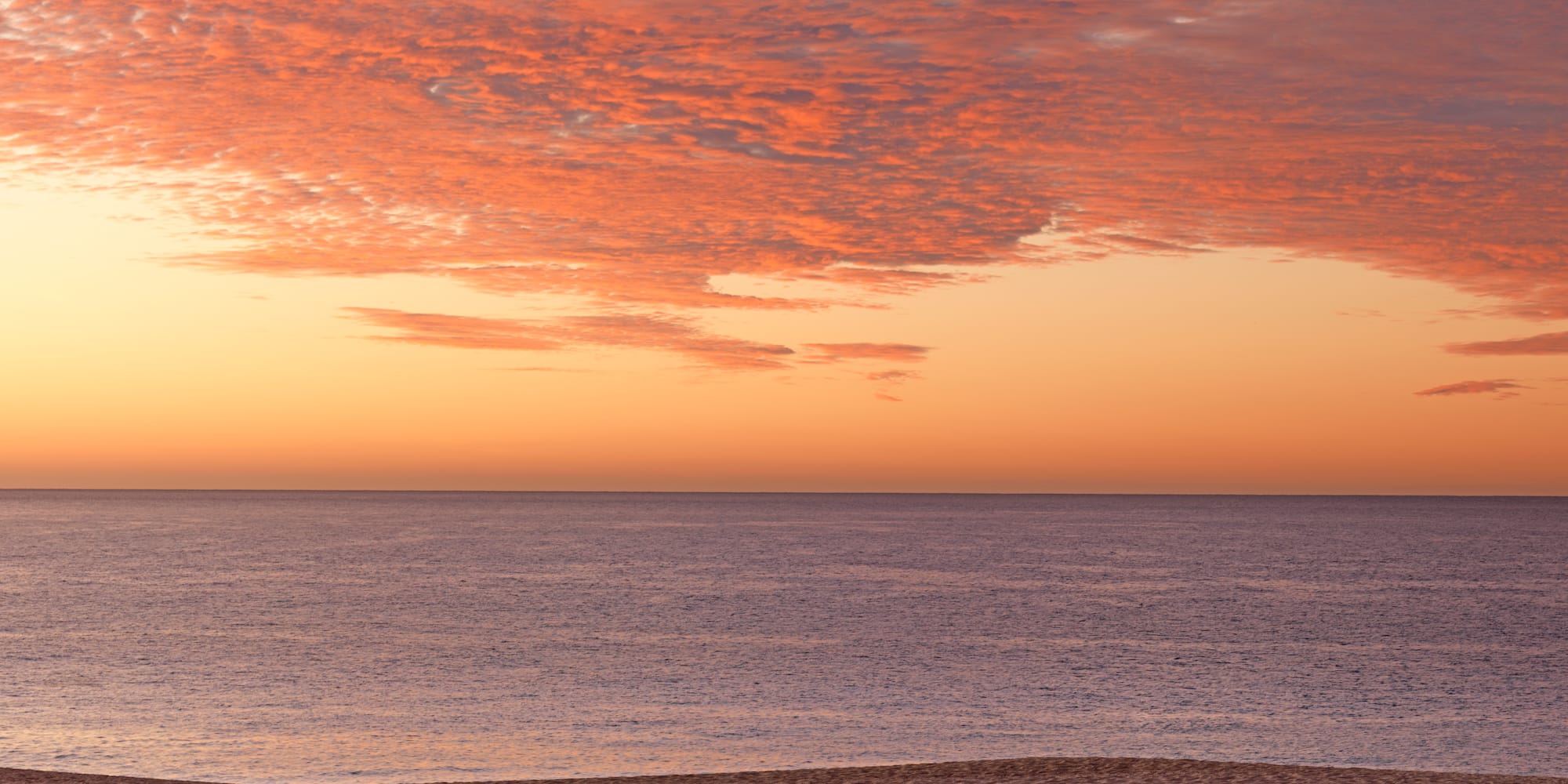 a beach with a body of water and a sunset