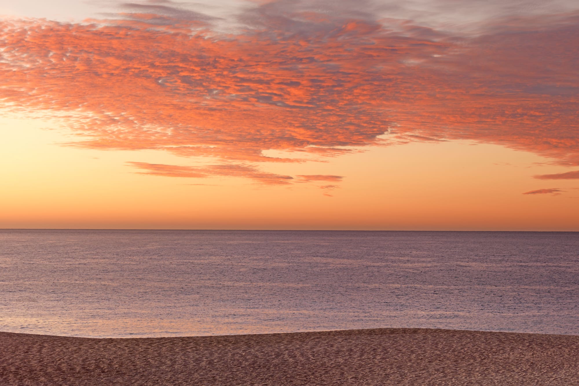 a beach with a body of water and a sunset