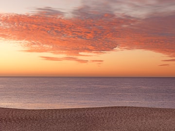 a beach with a body of water and a sunset