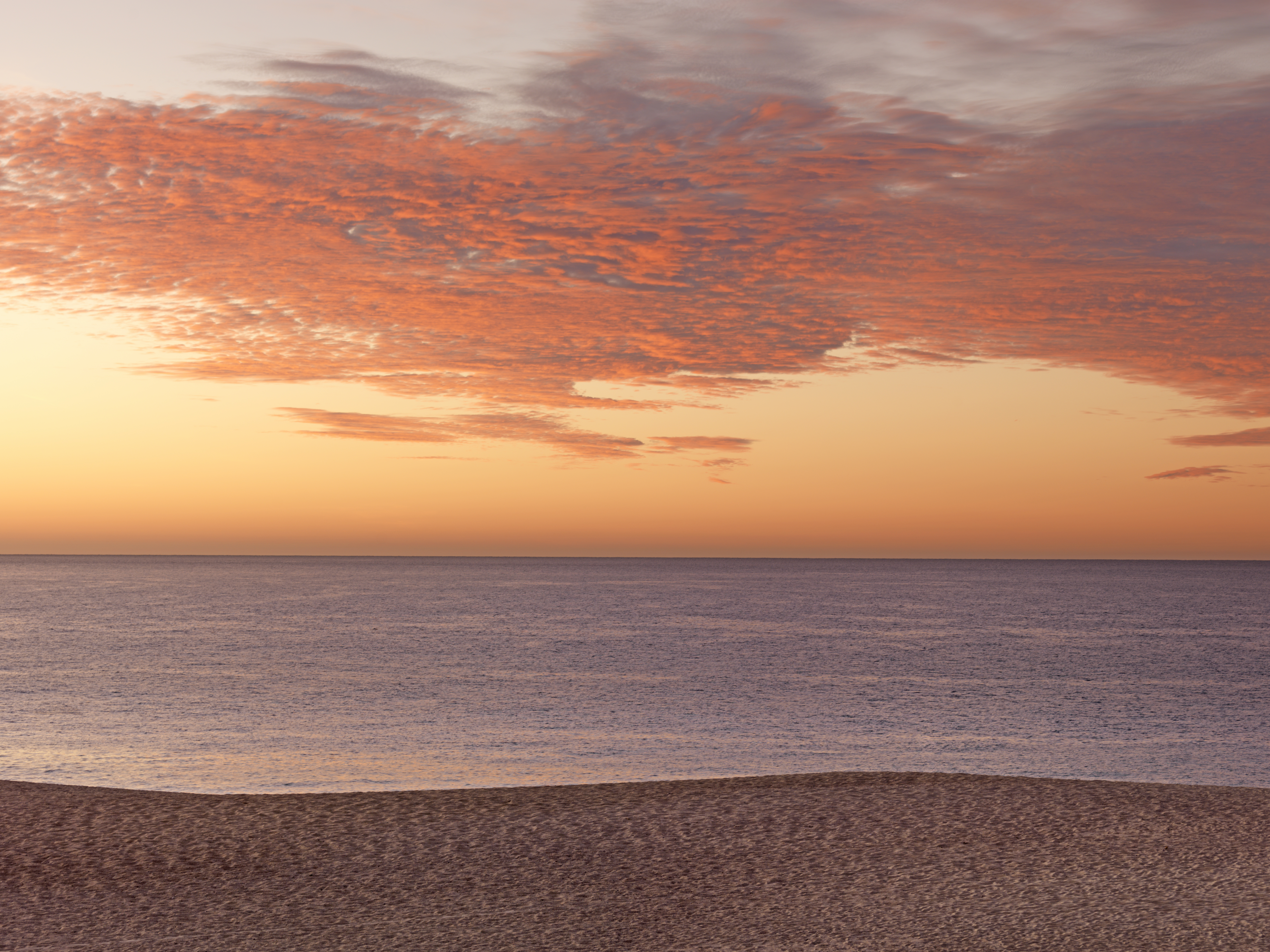 a beach with a body of water and a sunset