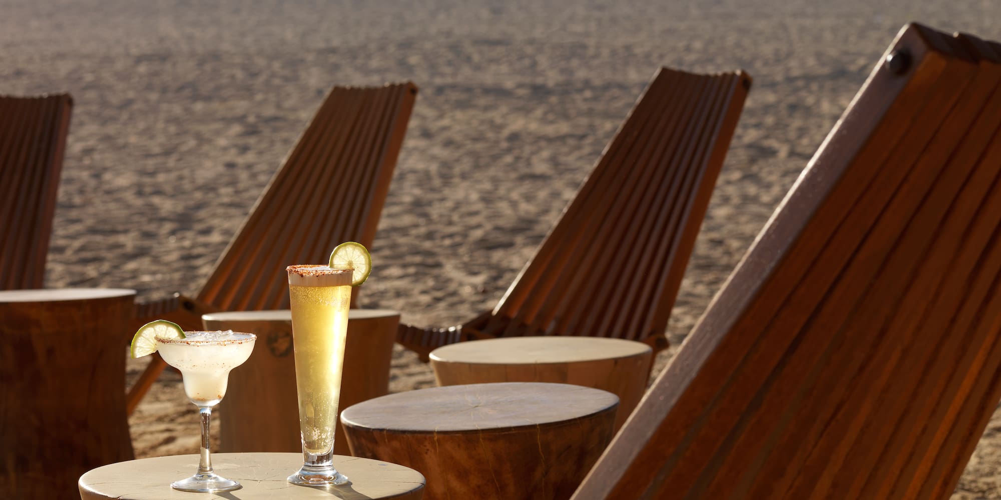 a table with drinks on it and chairs on the beach