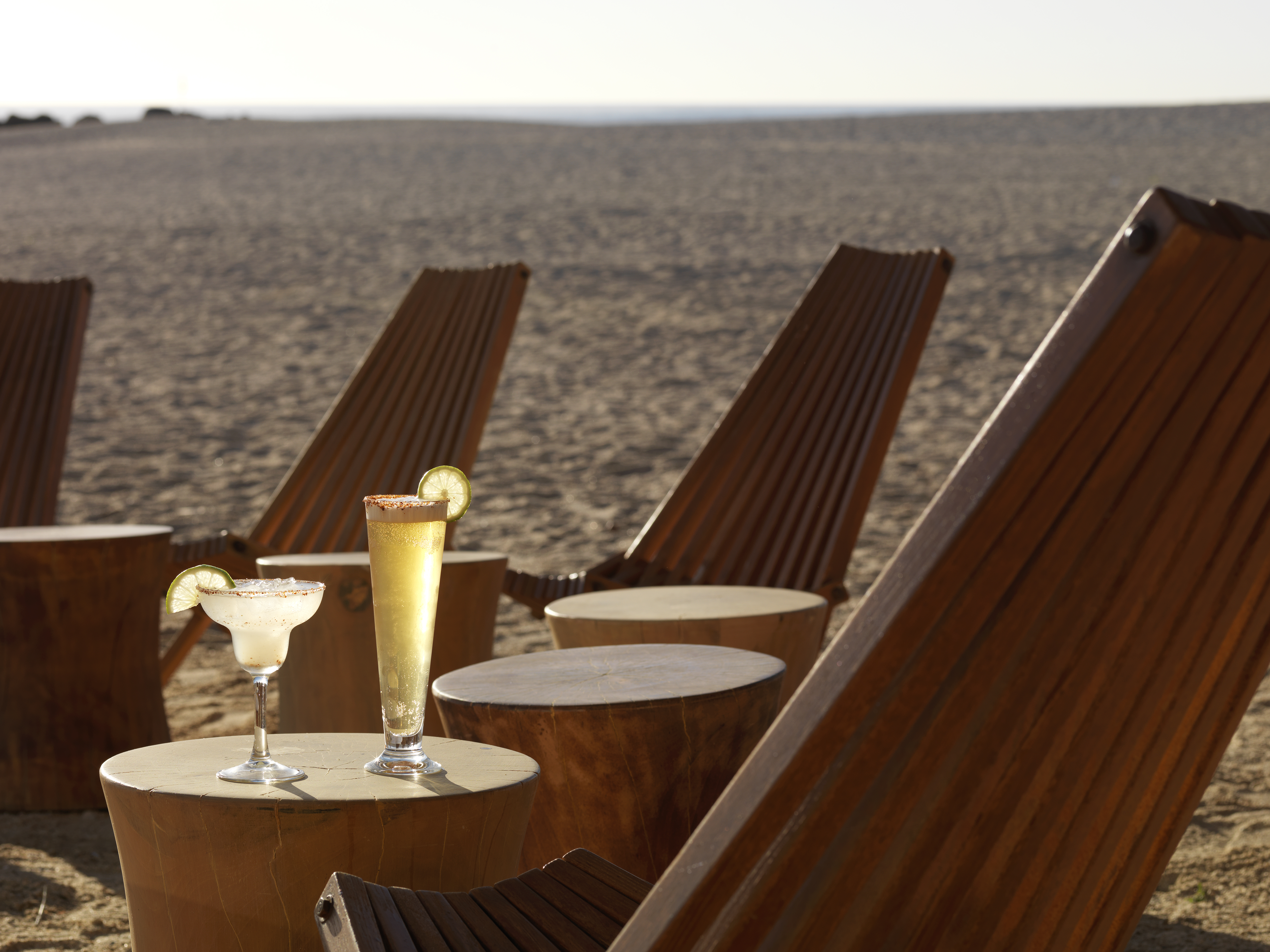 a table with drinks on it and chairs on the beach