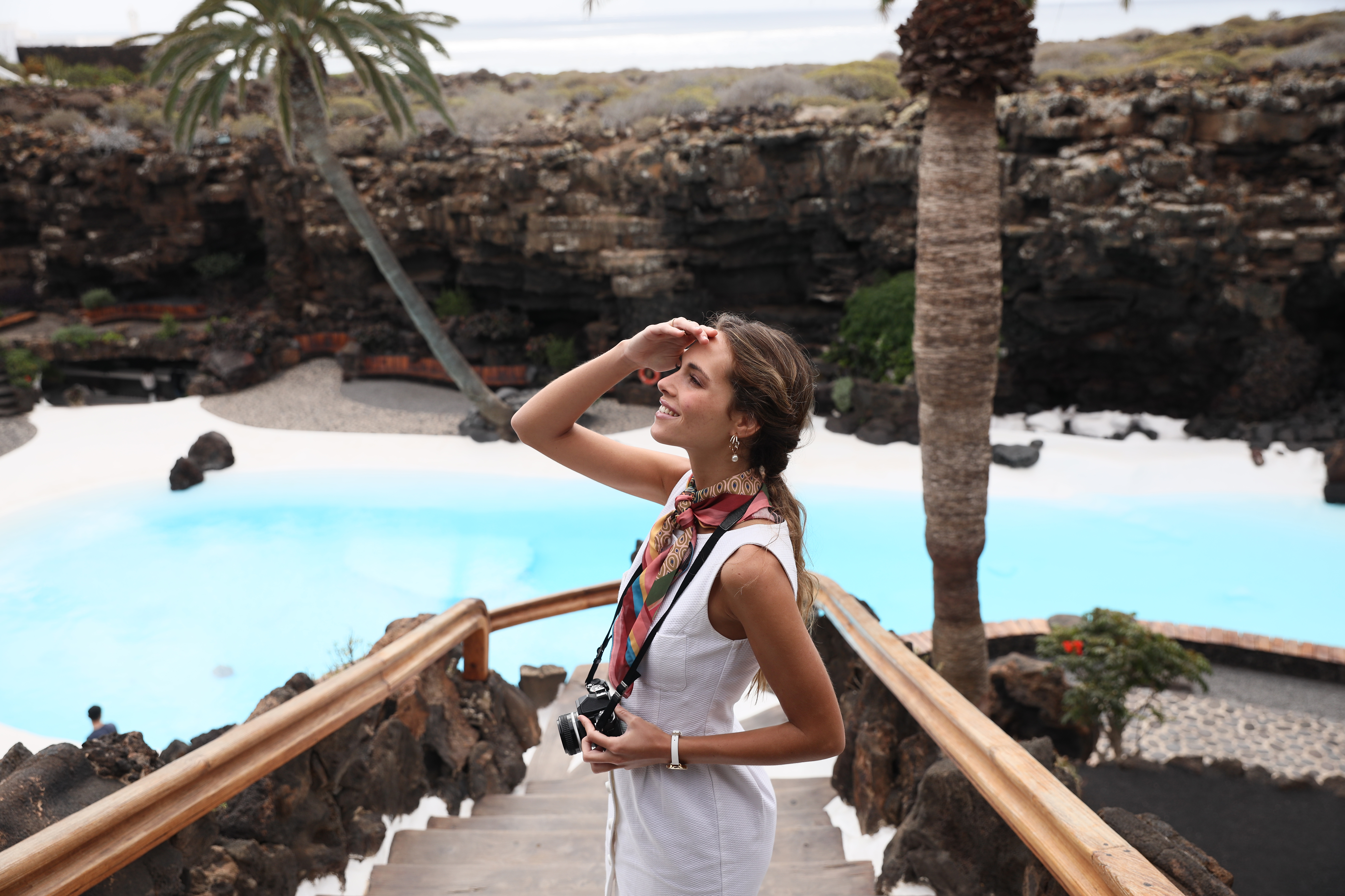 a woman standing on a staircase with a camera and palm trees