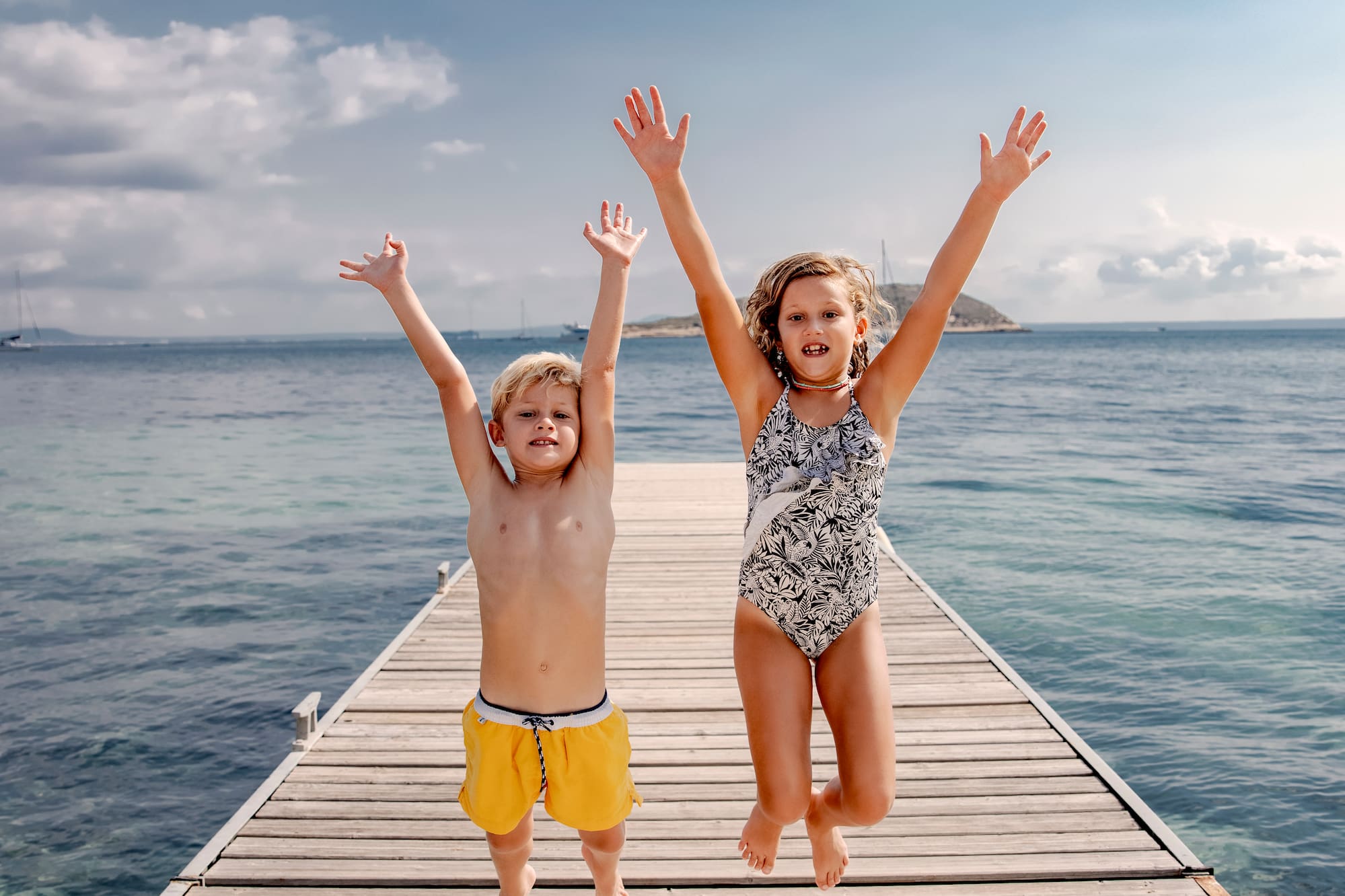 a boy and girl jumping on a dock