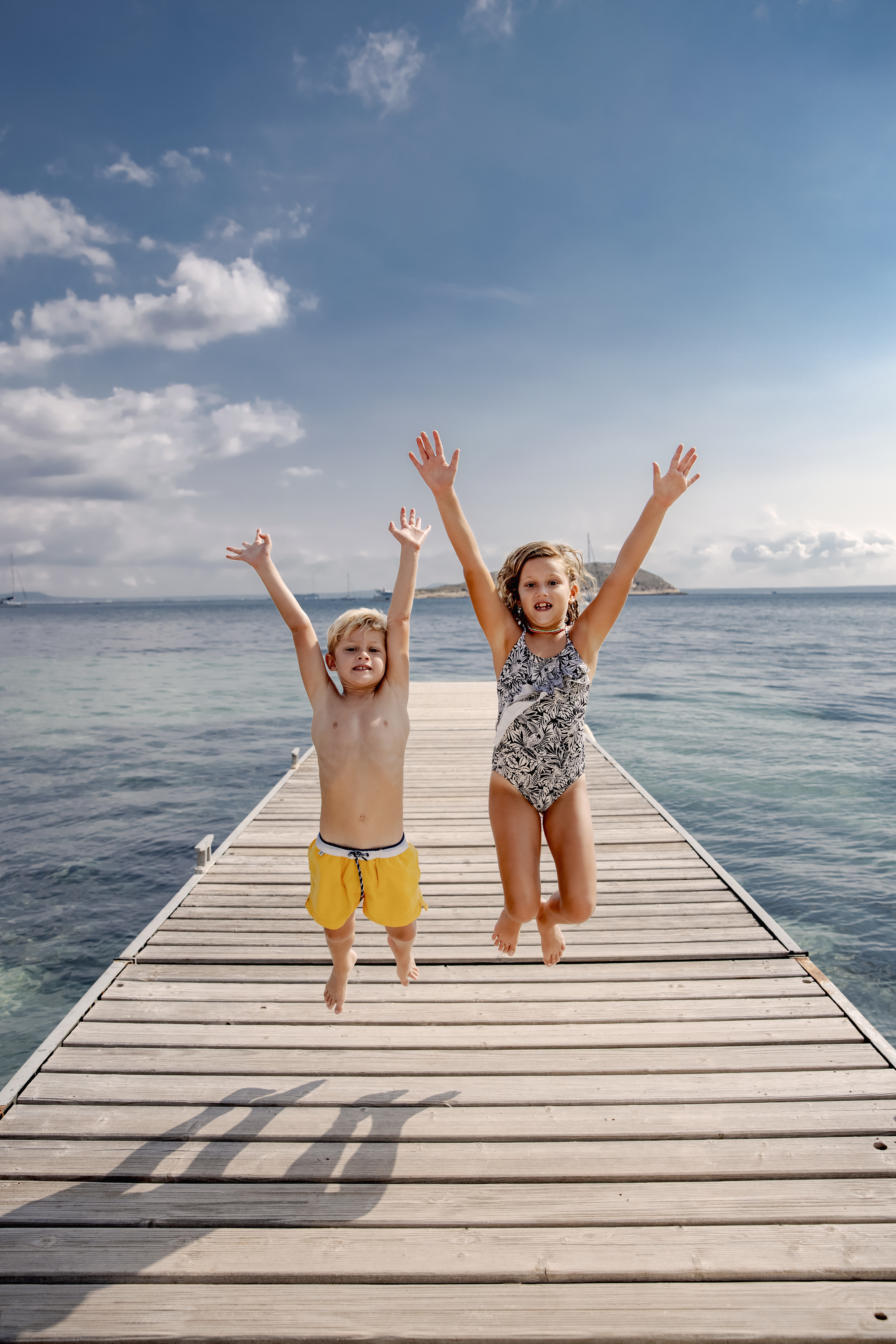 a boy and girl jumping on a dock