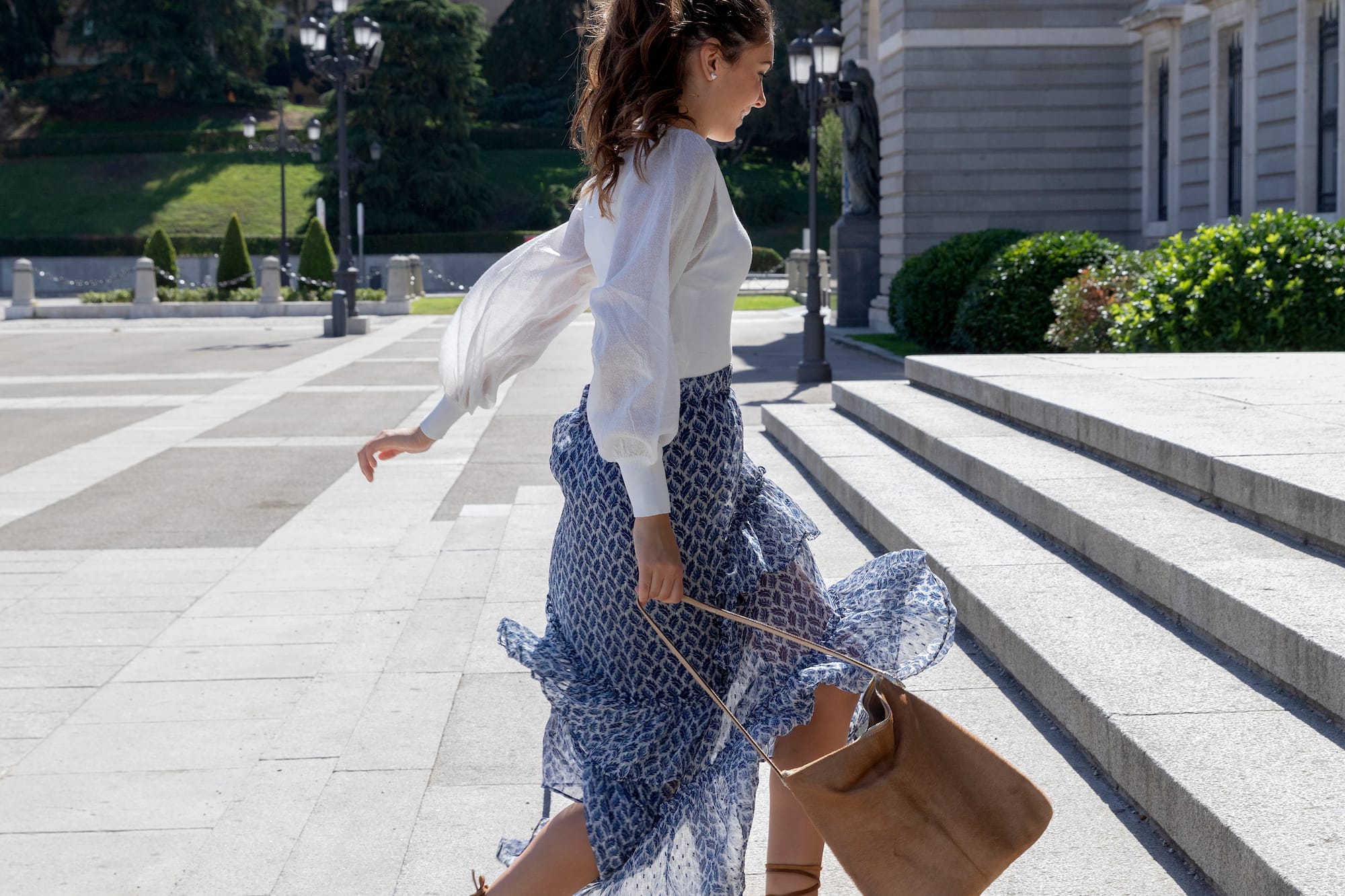 a woman in a skirt and sandals walking up steps