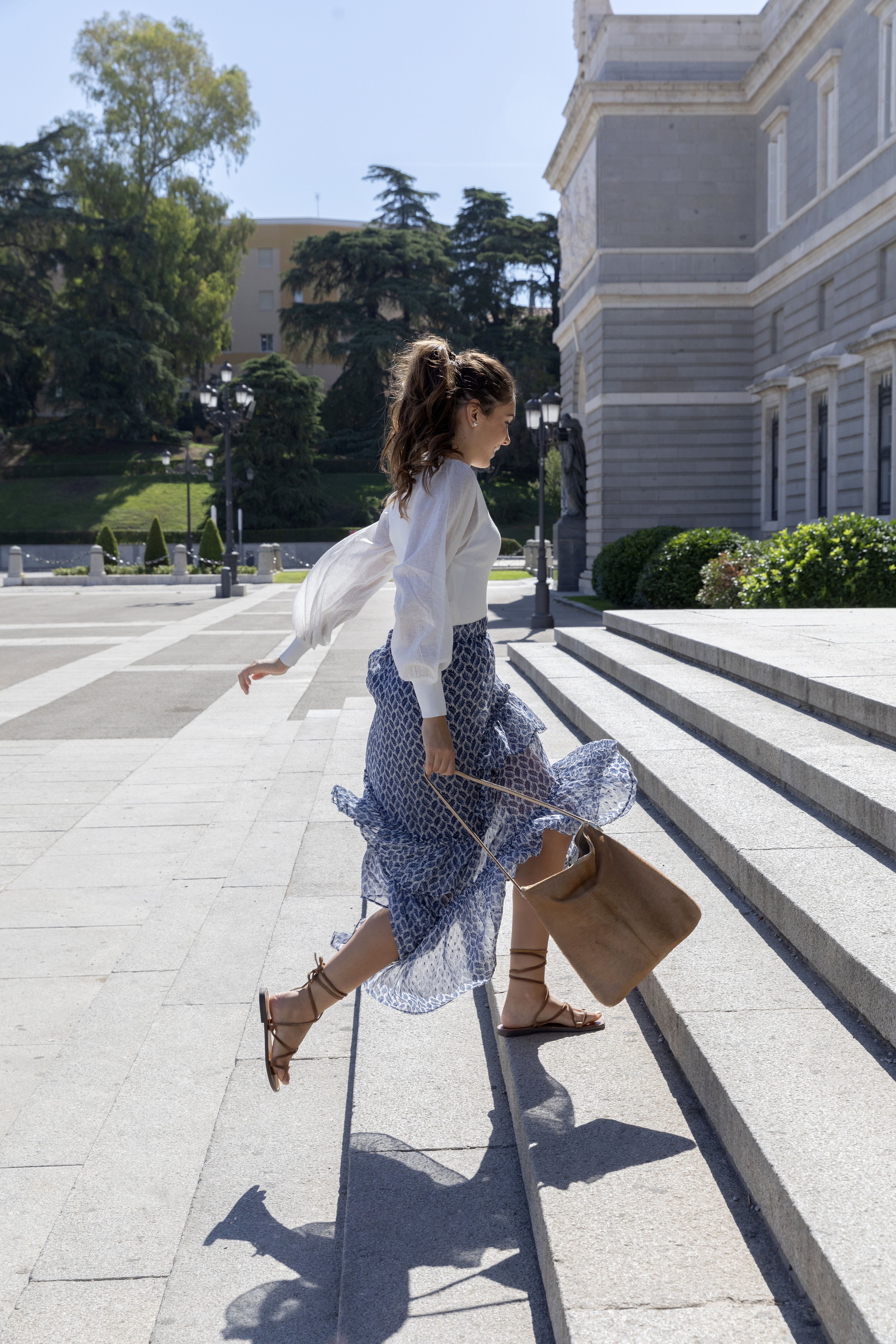 a woman in a skirt and sandals walking up steps