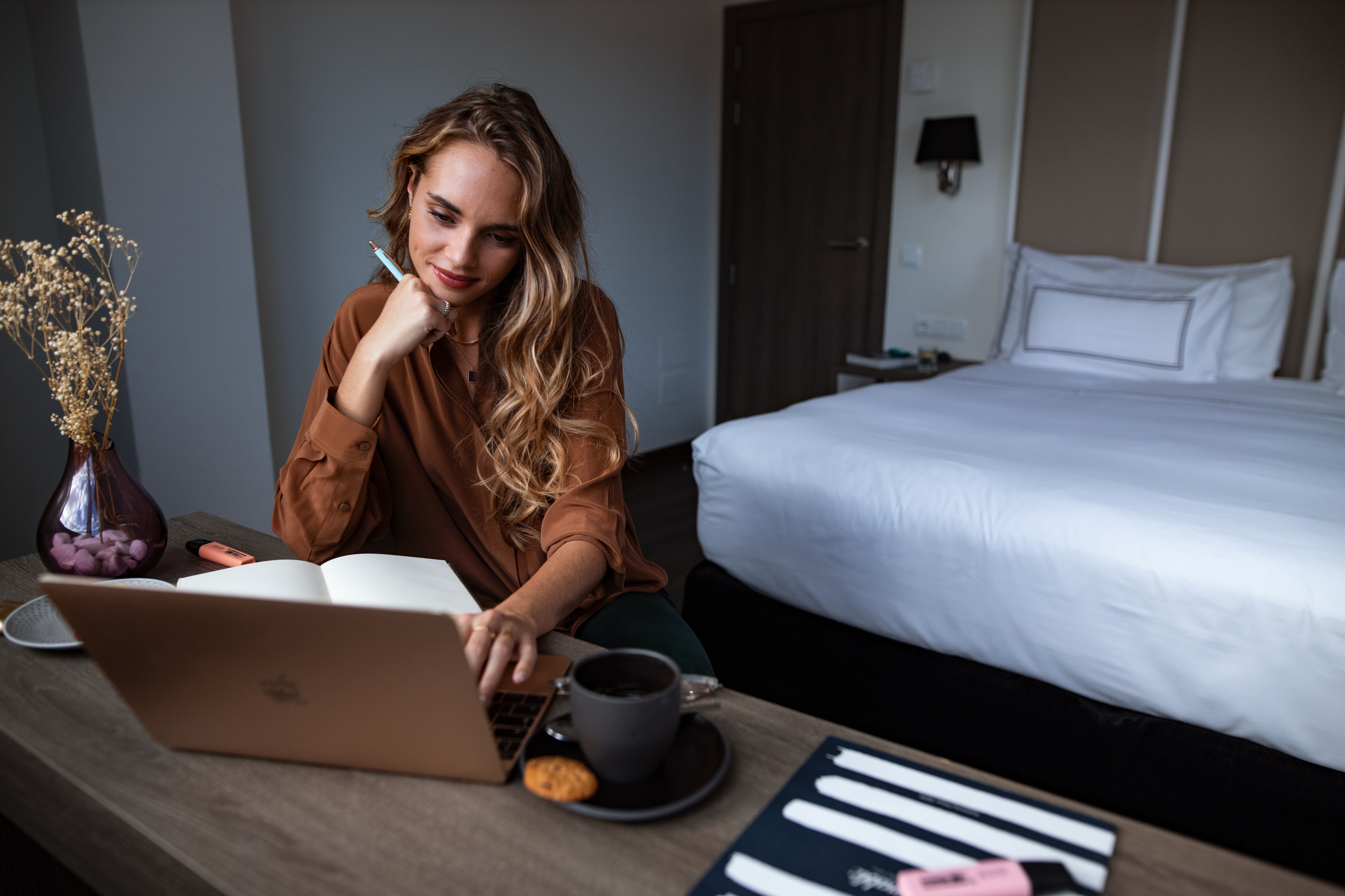 a woman sitting at a desk with a laptop and a cup of coffee