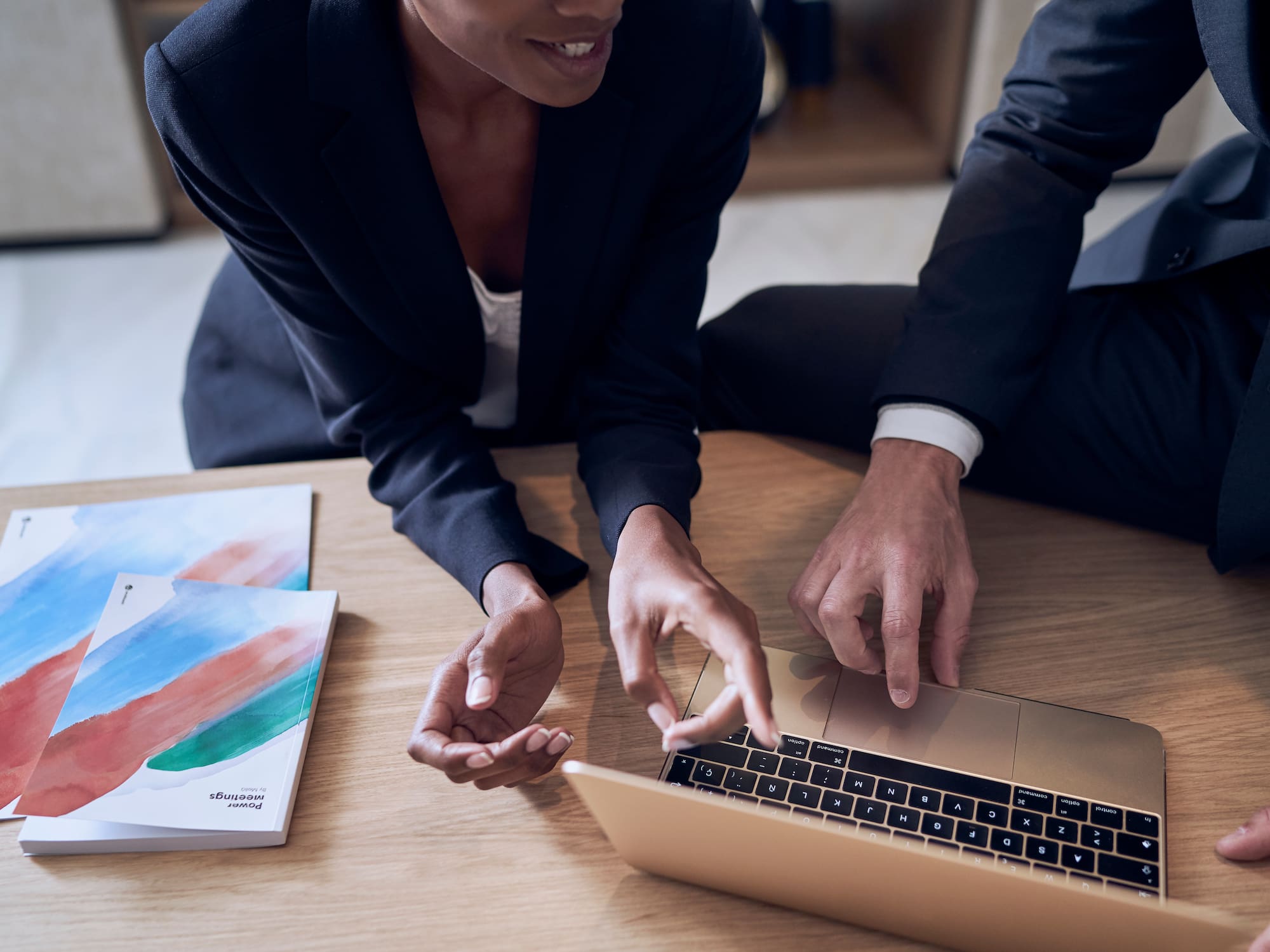 a man and woman sitting at a table looking at a laptop